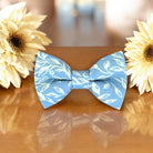 Blue & White Floral Bow Tie for groomsmen, wedding party and ring bearers surrounded by large flowers on wooden table.