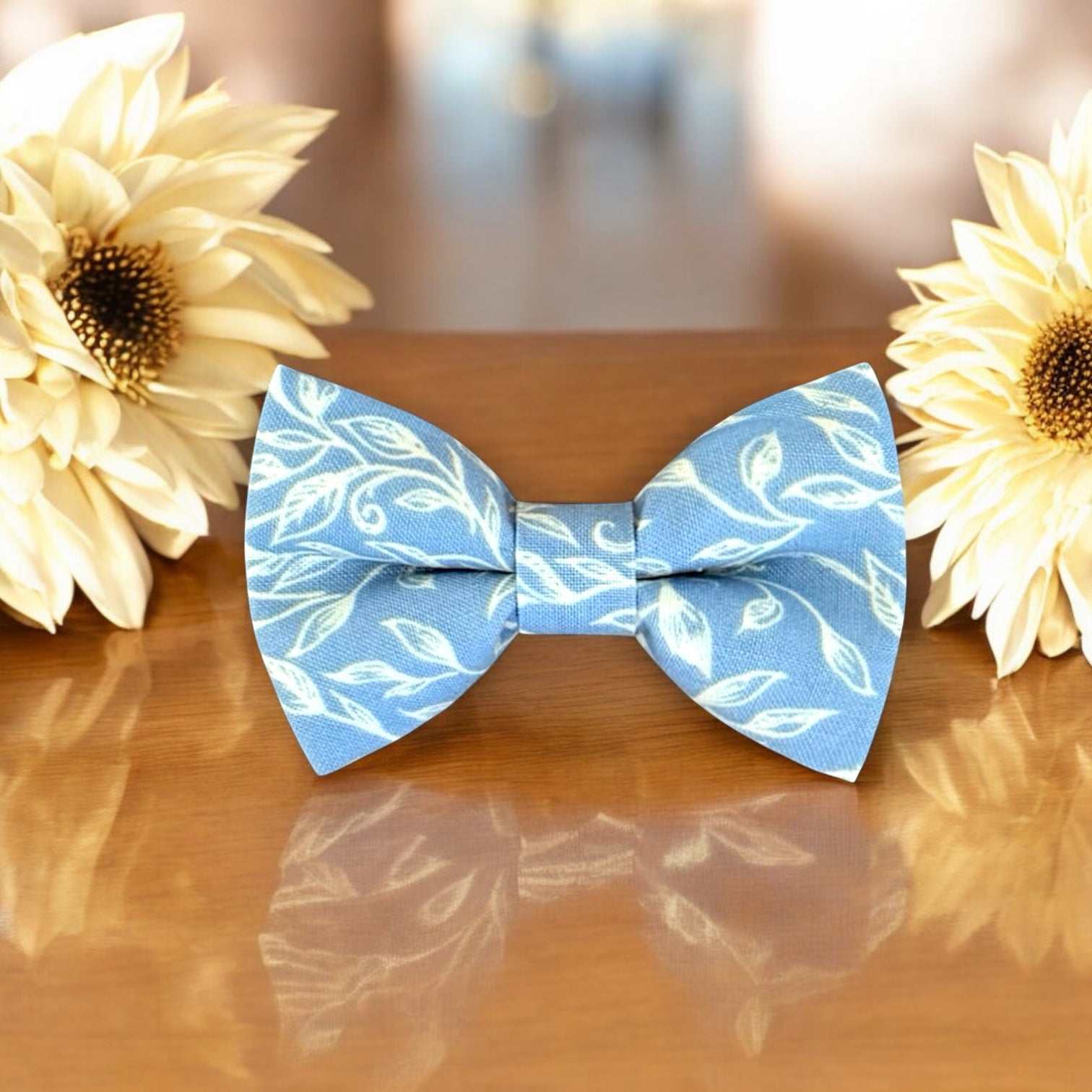 Blue & White Floral Bow Tie for groomsmen, wedding party and ring bearers surrounded by large flowers on wooden table.