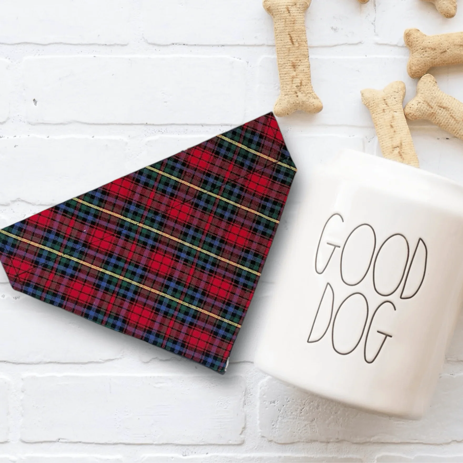 Red and black plaid Christmas dog bandana with gold stripes on white surface