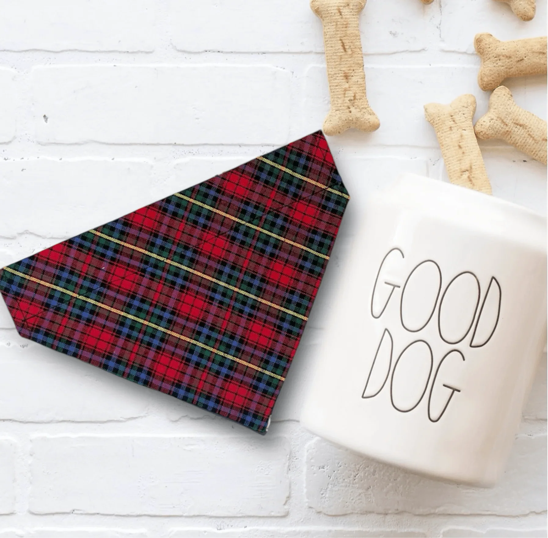 Red and black plaid Christmas dog bandana with gold stripes on white surface