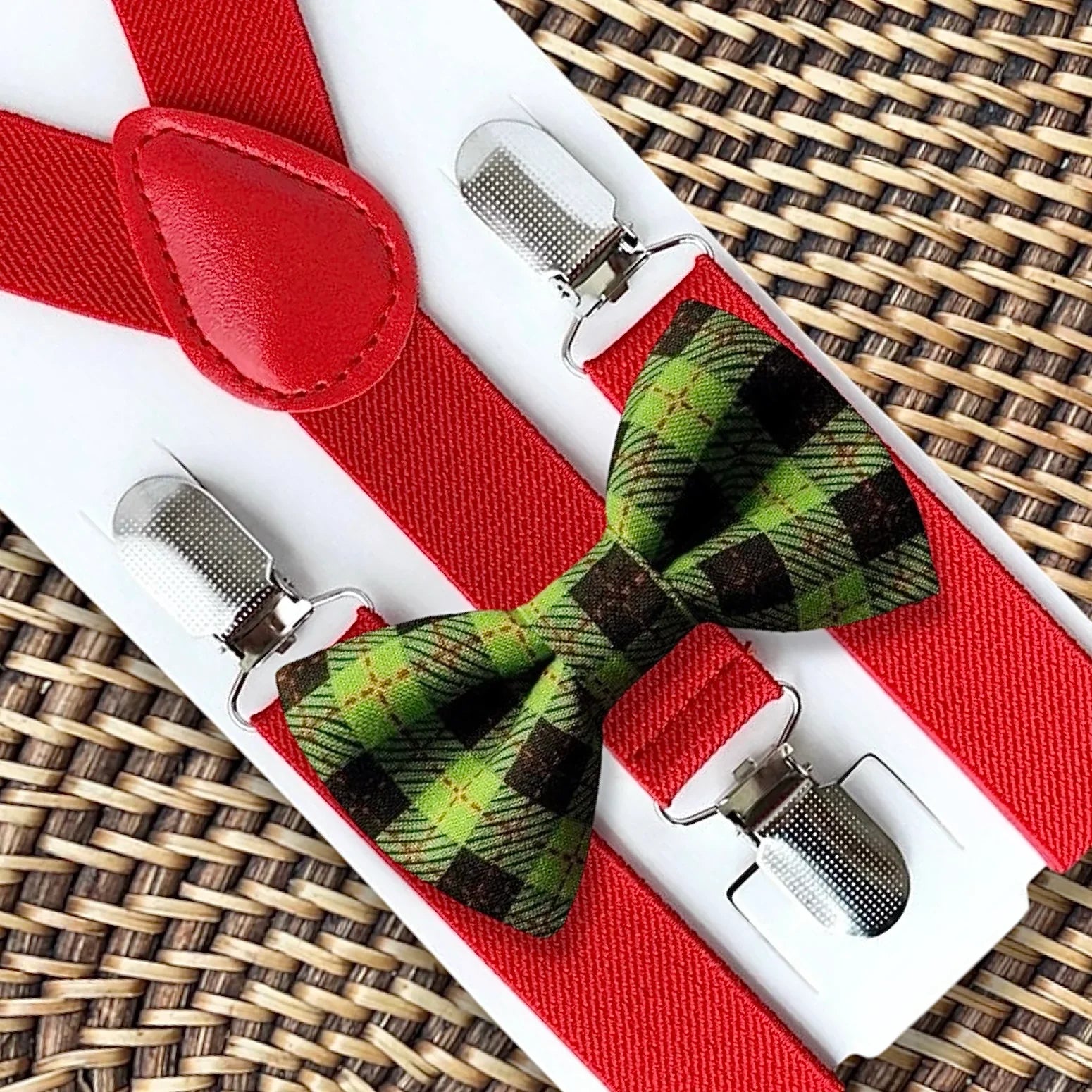 Green plaid bow tie with red suspenders displayed on a white card