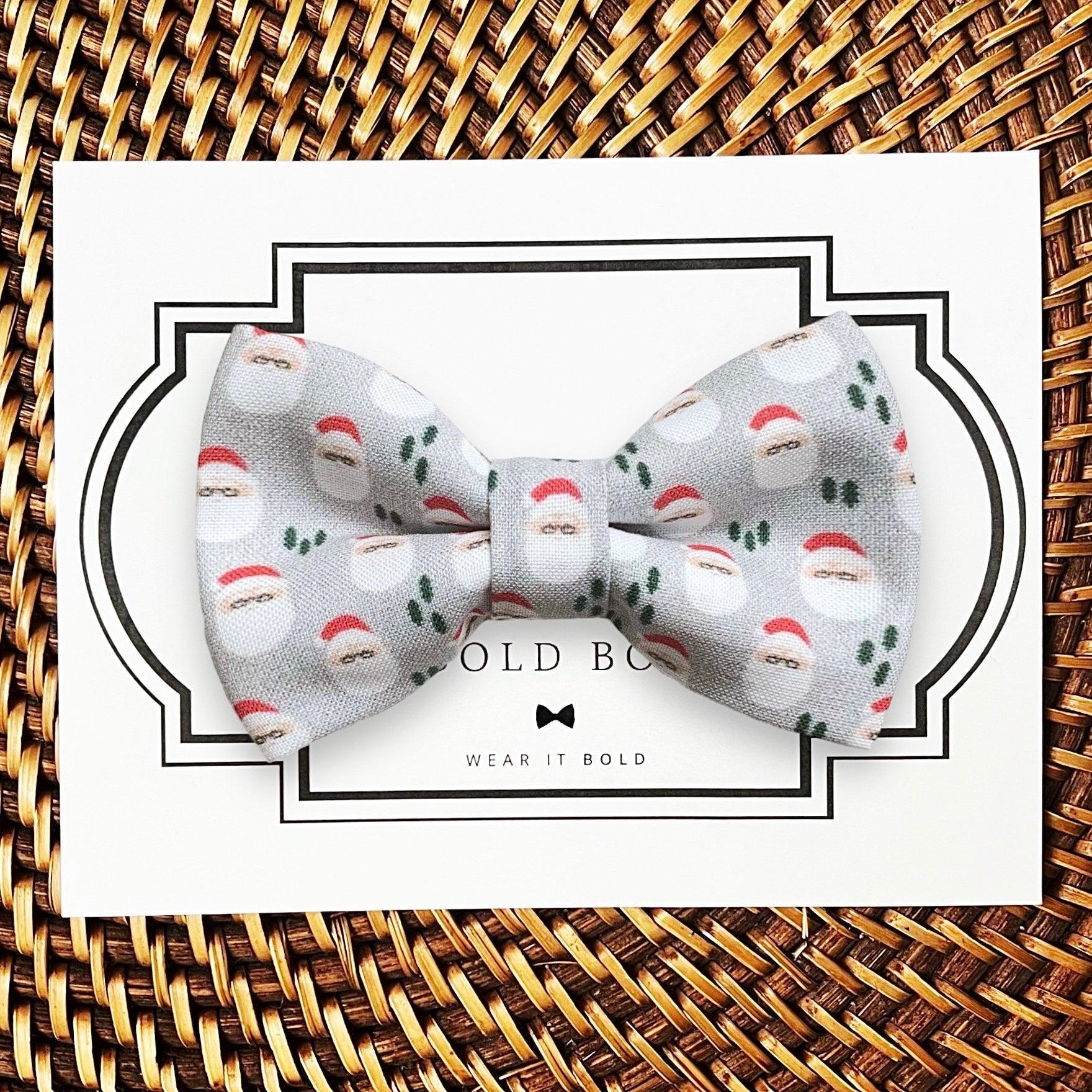 Product graphic showcasing the back of a pre-tied bow tie in a red and black buffalo plaid pattern, resting on a rustic wood surface. Two black elastic loops are attached to the center knot to slide onto a pet collar. Overlay text reads: Back of Bow Tie (may not be actual bow tie in listing).