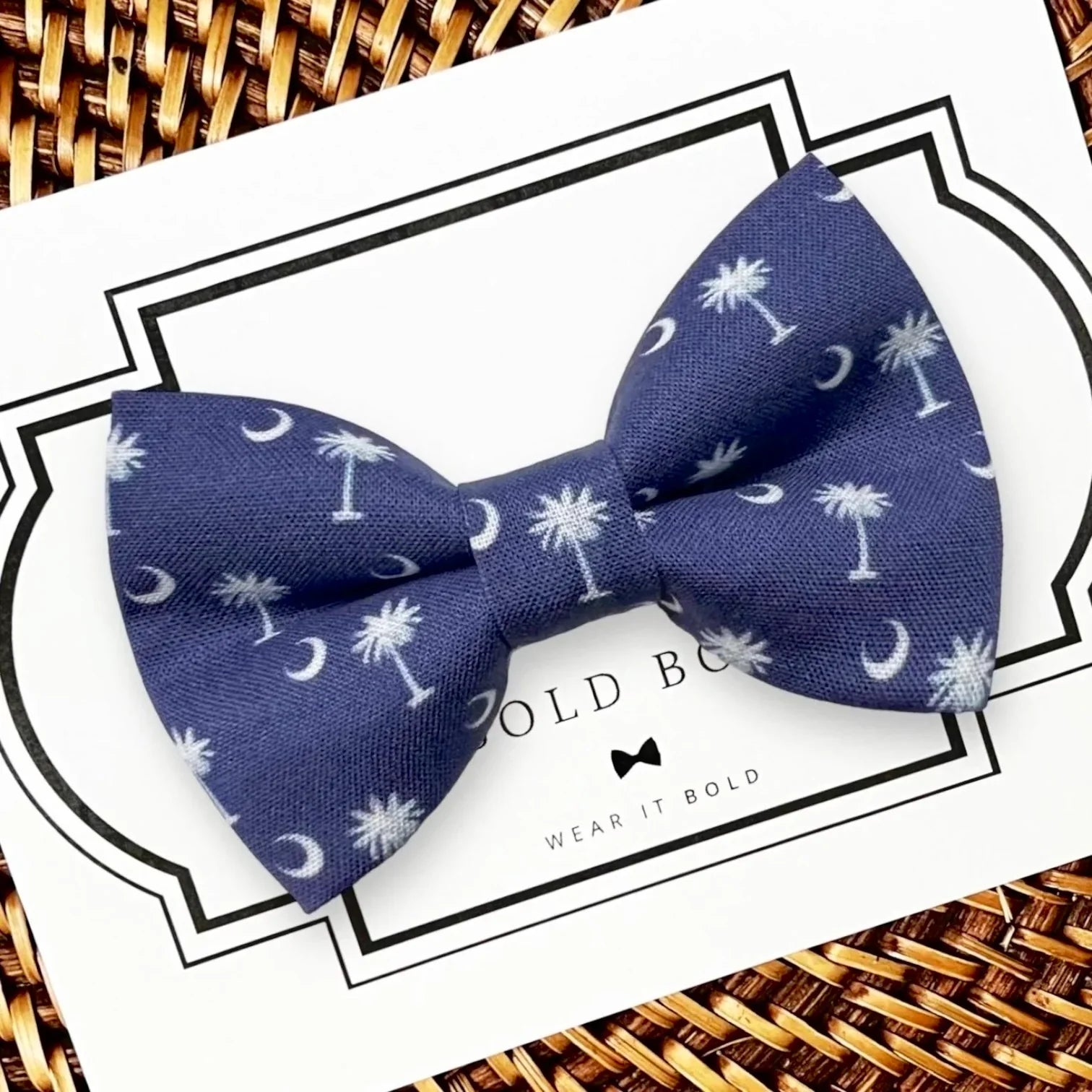 Blue bow tie with white palm trees and crescent moons on a white display card