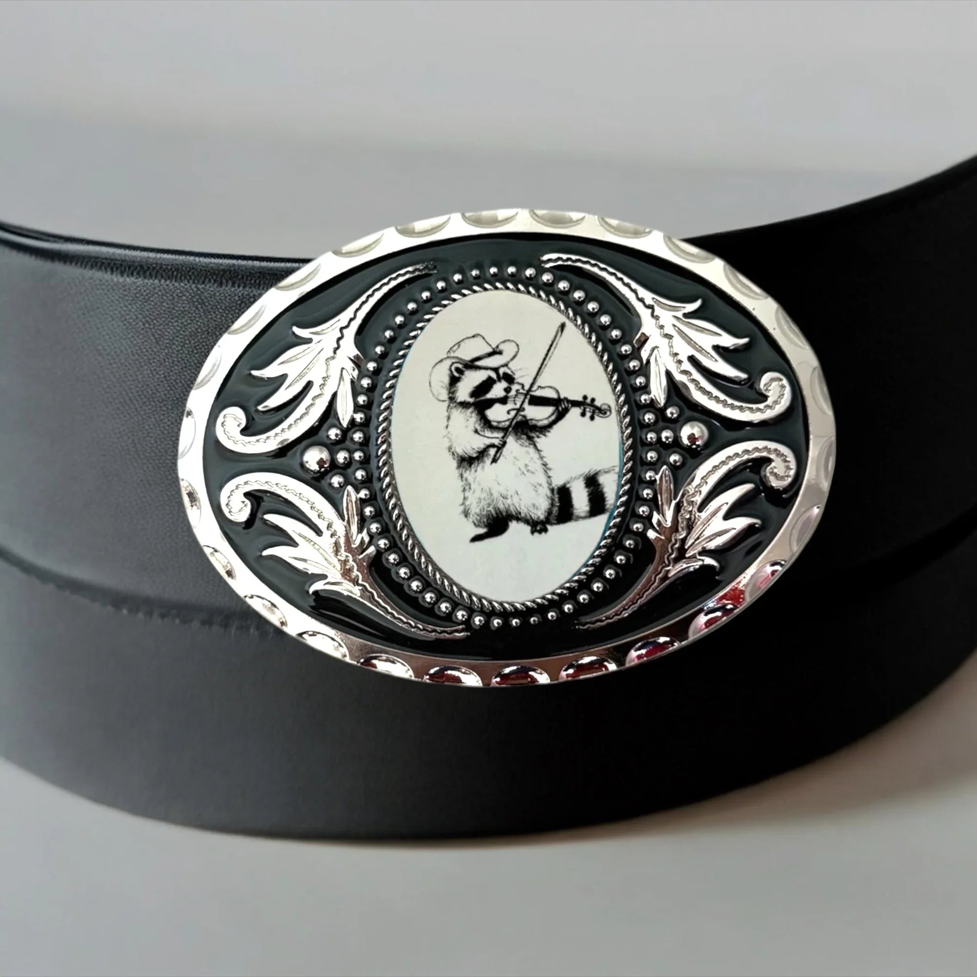 Funny raccoon belt buckle on black leather belt.