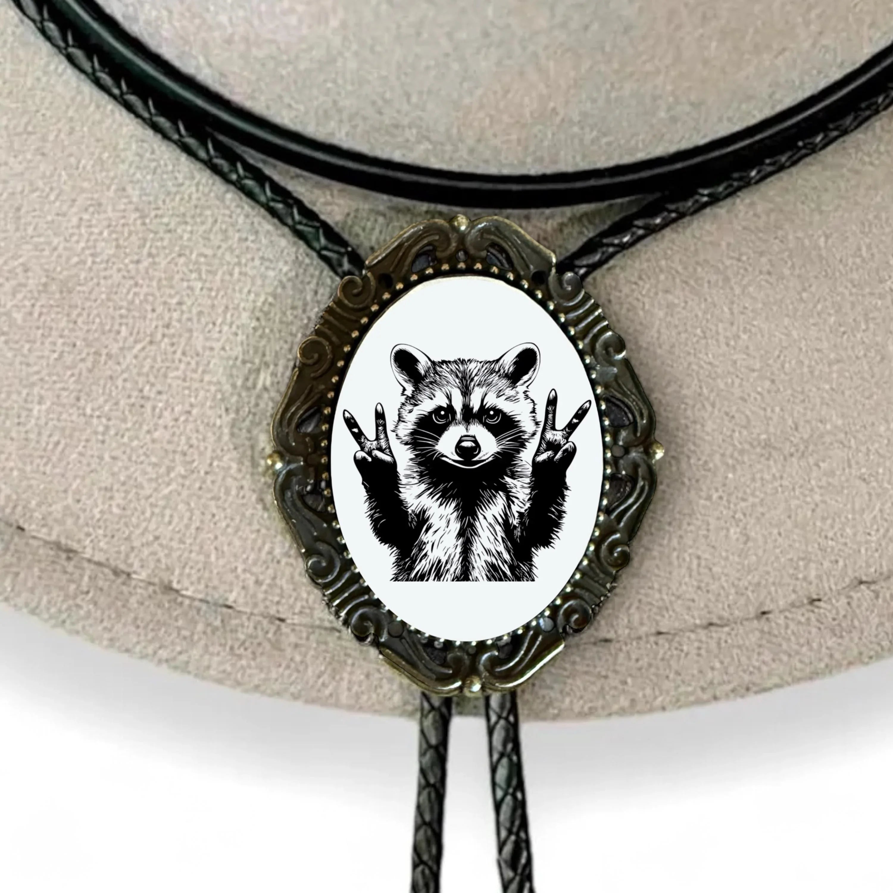 Infographic from The Bold Bow Tie titled Bolo Tie Features. Right: A vintage-style bolo tie with a blue and white cowboy riding a horse illustration inside an ornate bronze filigree frame on a black braided cord. Left: Lines connect the image to three checkmark features: Handmade, 39" Long Cord, and Pendant is 1.5" (L) x 1.25" (W). Bottom text reads Perfect Addition to Your Outfit.