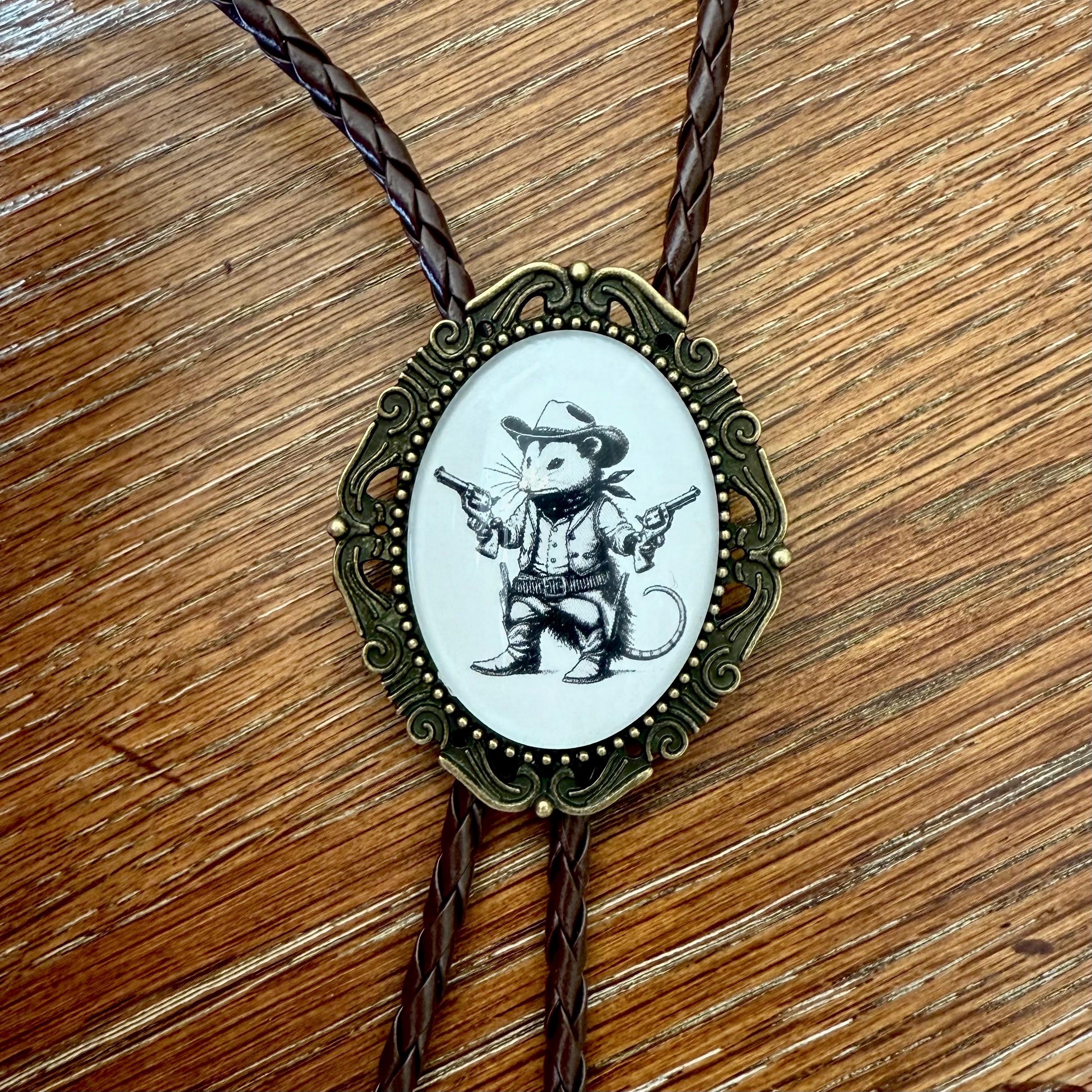Bolo tie with a cowboy possum design on a wooden surface