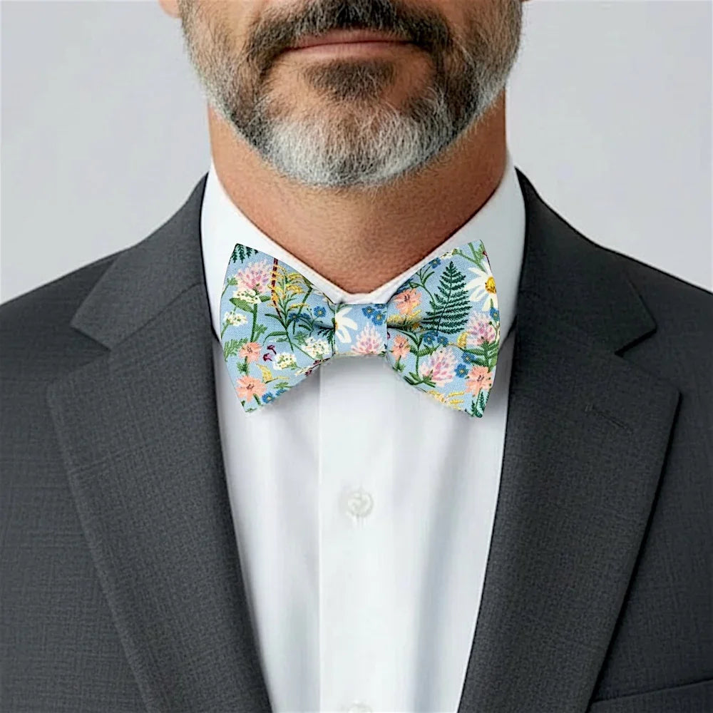 Size chart for pre-tied bow ties from The Bold Bow Tie detailing measurements across three sizes. Small is 3.5 inches wide and recommended for ages 6 months to 5 years. Medium is 4 inches wide and recommended for ages 6 to 12 years. Large is 4.5 inches wide and recommended for ages 13 years and up. Visual icons illustrate the relative sizes with horizontal arrows showing that width is measured from wingtip to wingtip. Bottom text notes that all bow ties are pre-tied and ready to add to your outfit.