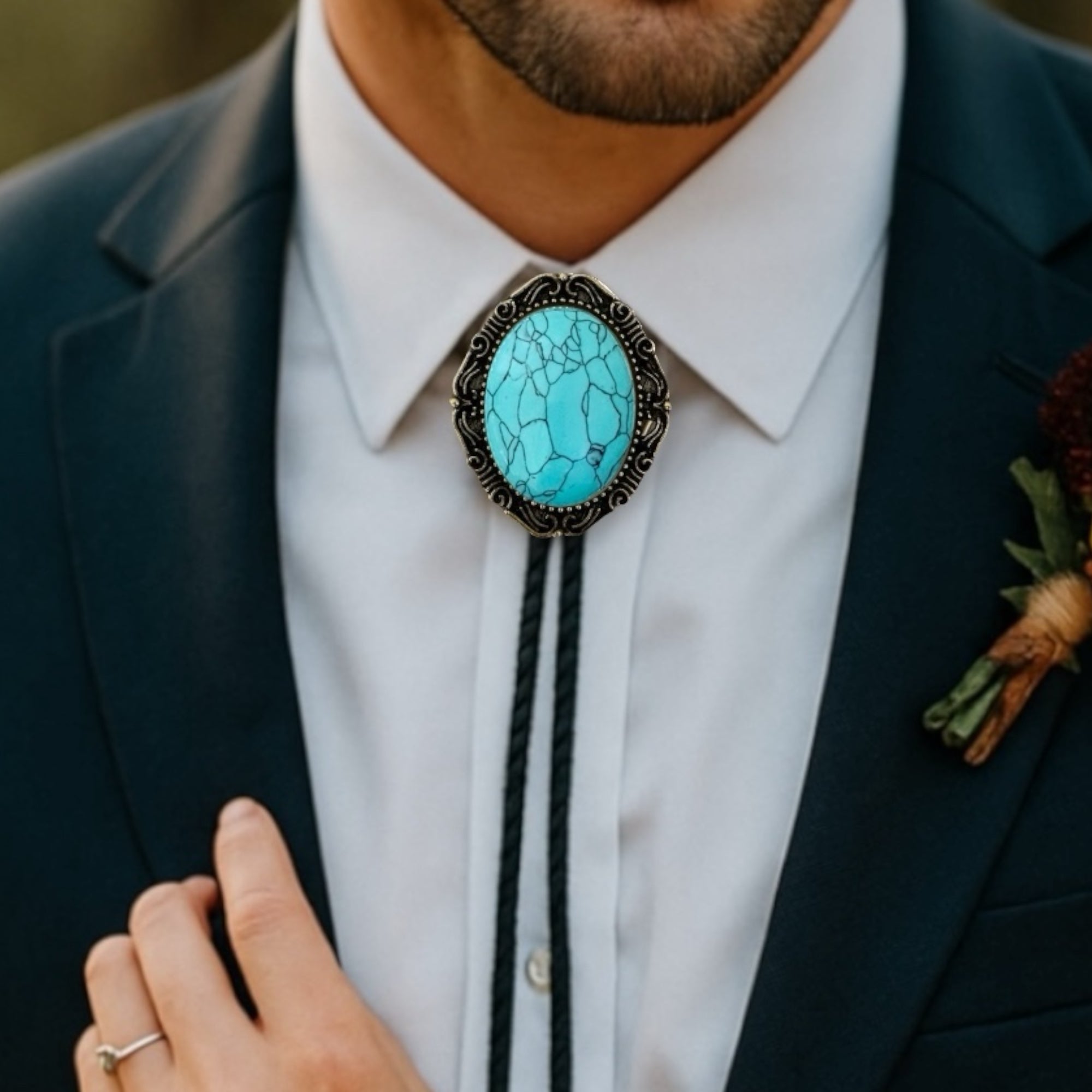 Groomsman wearing a dark suit with a white shirt and turquoise stone bolo tie in a wedding.