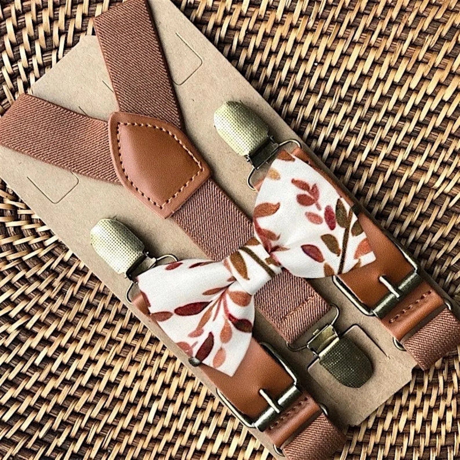 Brown suspenders with terracotta floral patterned clips on a woven surface