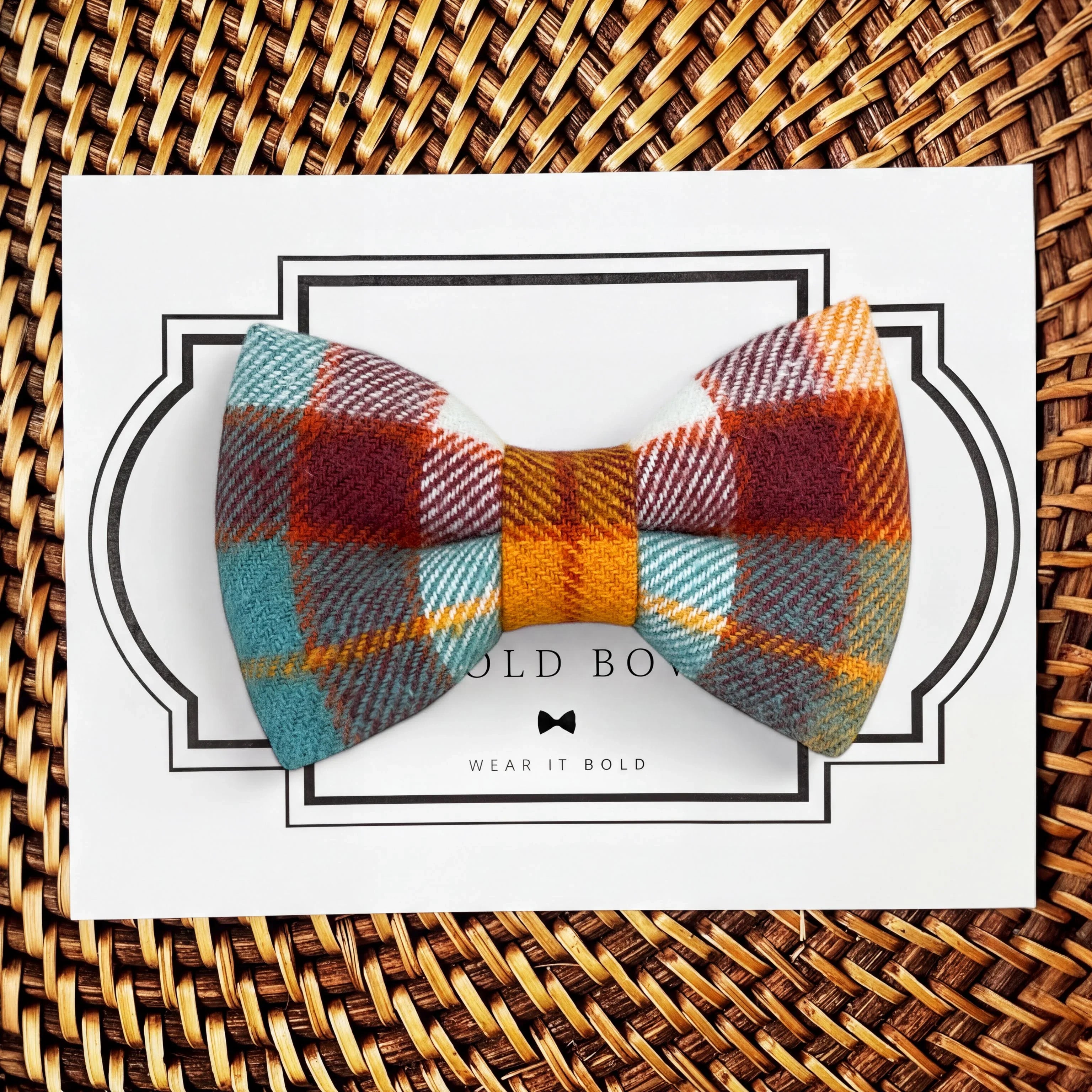 Product graphic showcasing the back of a pre-tied bow tie in a red and black buffalo plaid pattern, resting on a rustic wood surface. Two black elastic loops are attached to the center knot to slide onto a pet collar. Overlay text reads: Back of Bow Tie (may not be actual bow tie in listing).