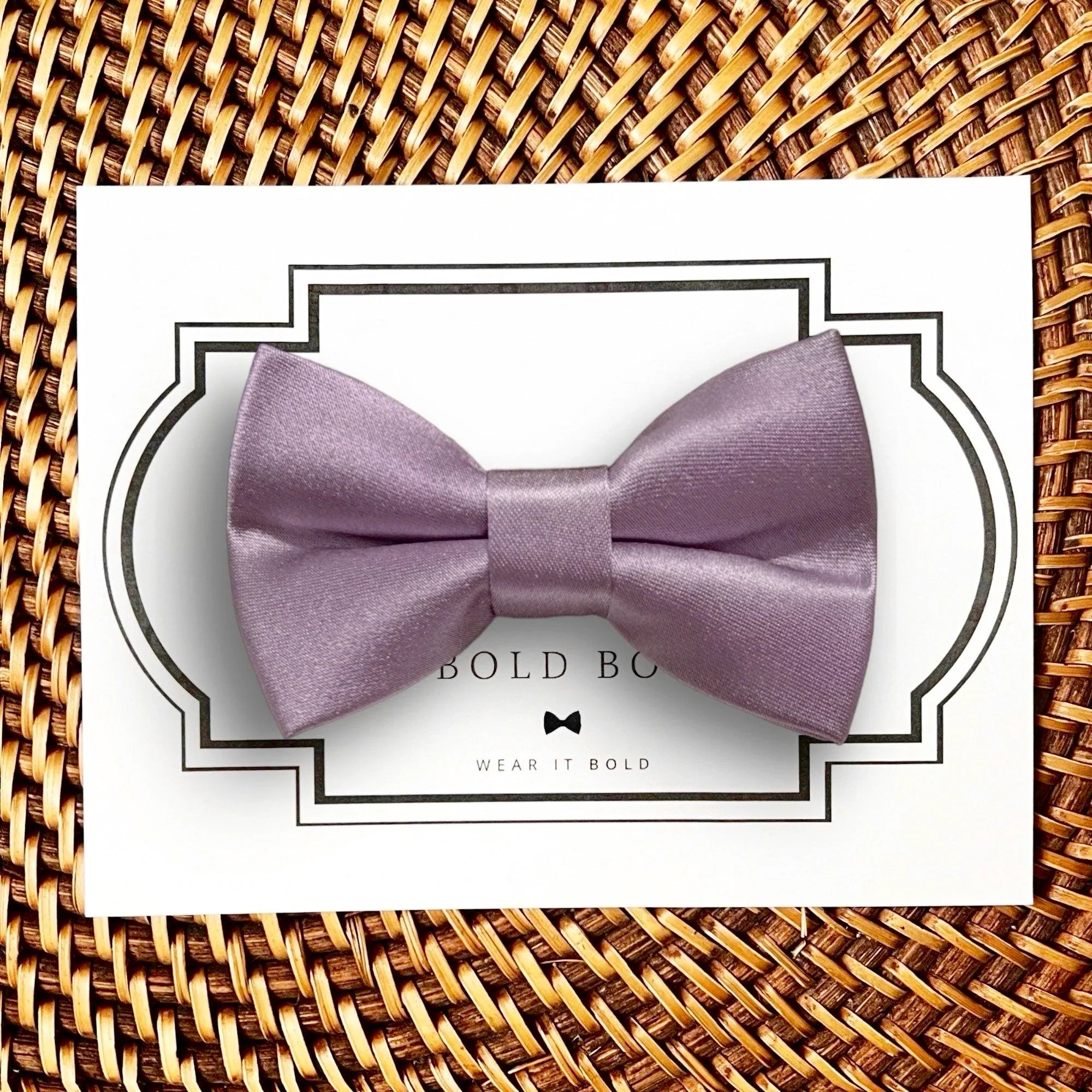 Product graphic showcasing the back of a pre-tied bow tie in a red and black buffalo plaid pattern, resting on a rustic wood surface. Two black elastic loops are attached to the center knot to slide onto a pet collar. Overlay text reads: Back of Bow Tie (may not be actual bow tie in listing).