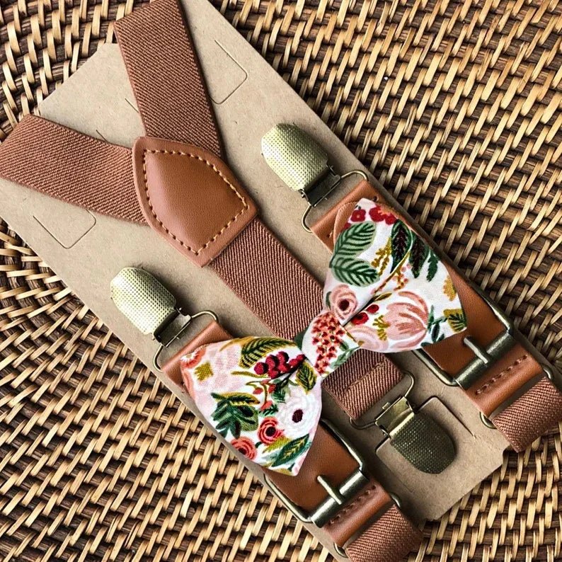 Rifle Paper Co floral bow tie with cognac brown suspenders on a woven surface