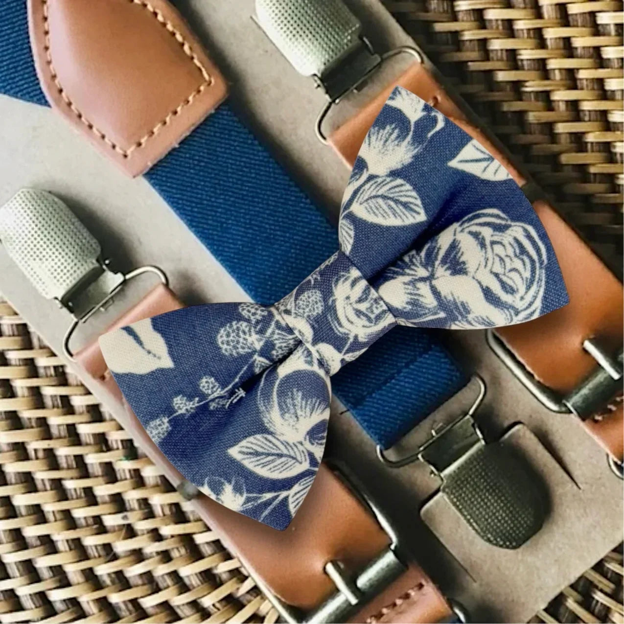 Blue floral bow tie with suspenders on a woven surface