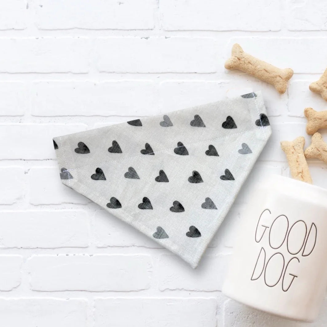 Gray boho heart bandana with black hearts on a white surface with dog treats and a 'Good Dog' mug.