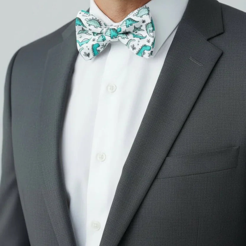Man wearing a gray suit with a white shirt and a dinosaur bow tie against a light gray background