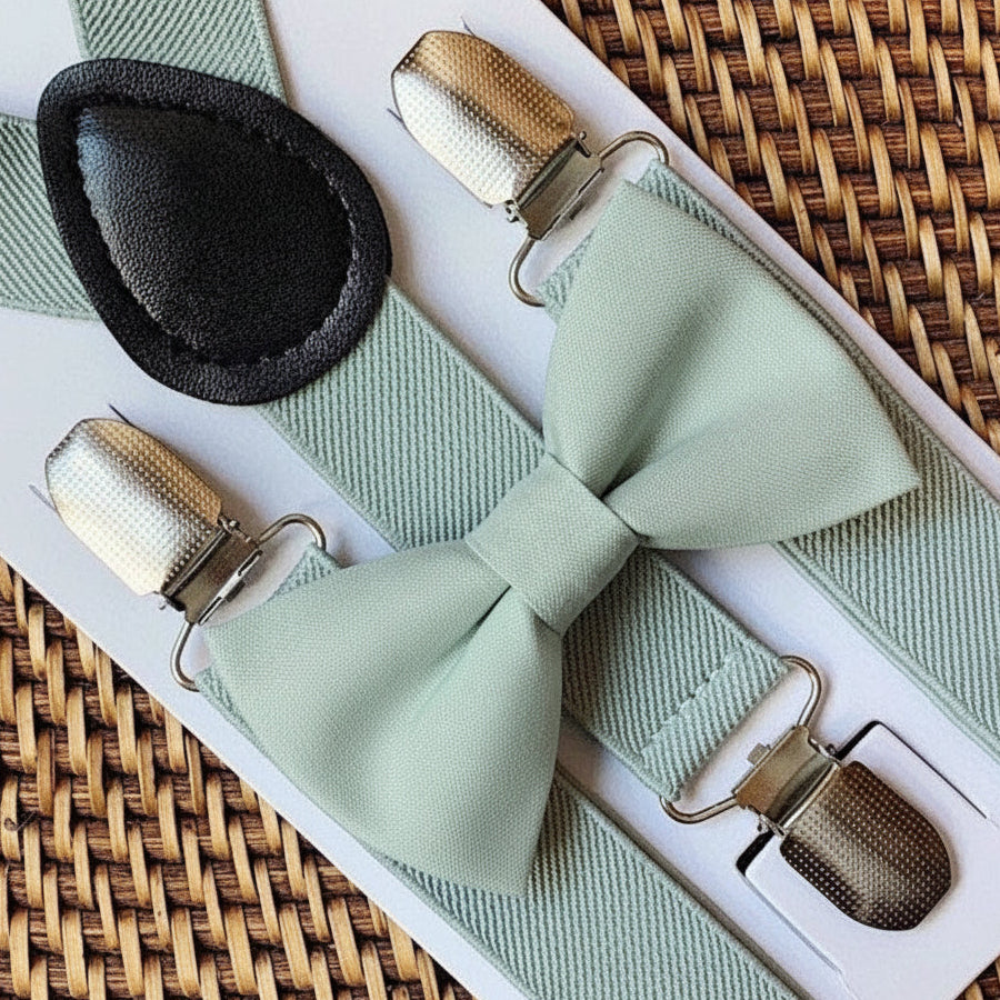 Sage green bow tie and sage green suspenders for a wedding displayed on a woven tray by The Bold Bow Tie.