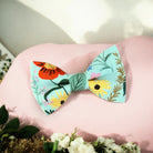 Blue and green floral men’s bow tie for weddings, groomsmen or ring bearers on a pink overlay.