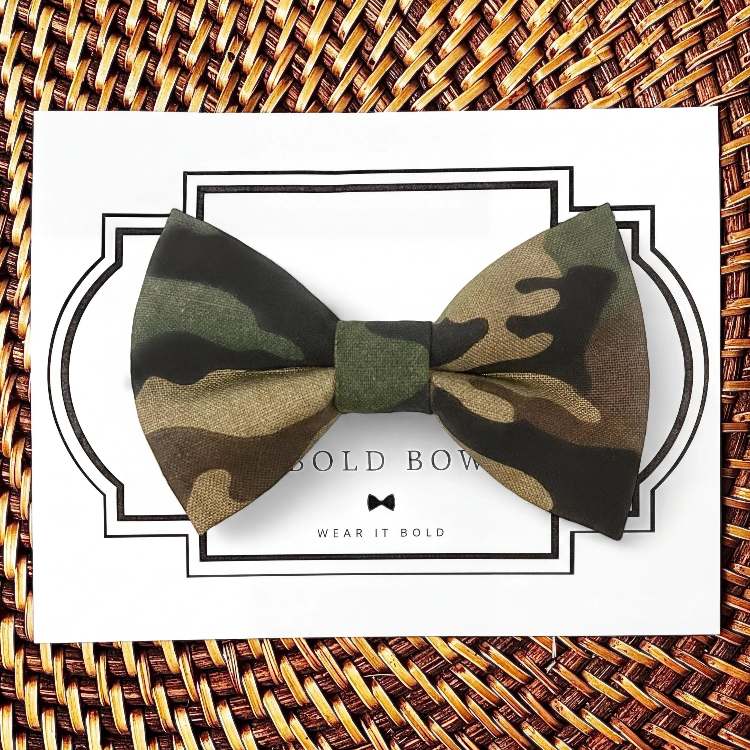 A camouflage bow tie is displayed on a white card with a black border, accompanied by the text "BOLD BOWL WEAR IT BOLD".