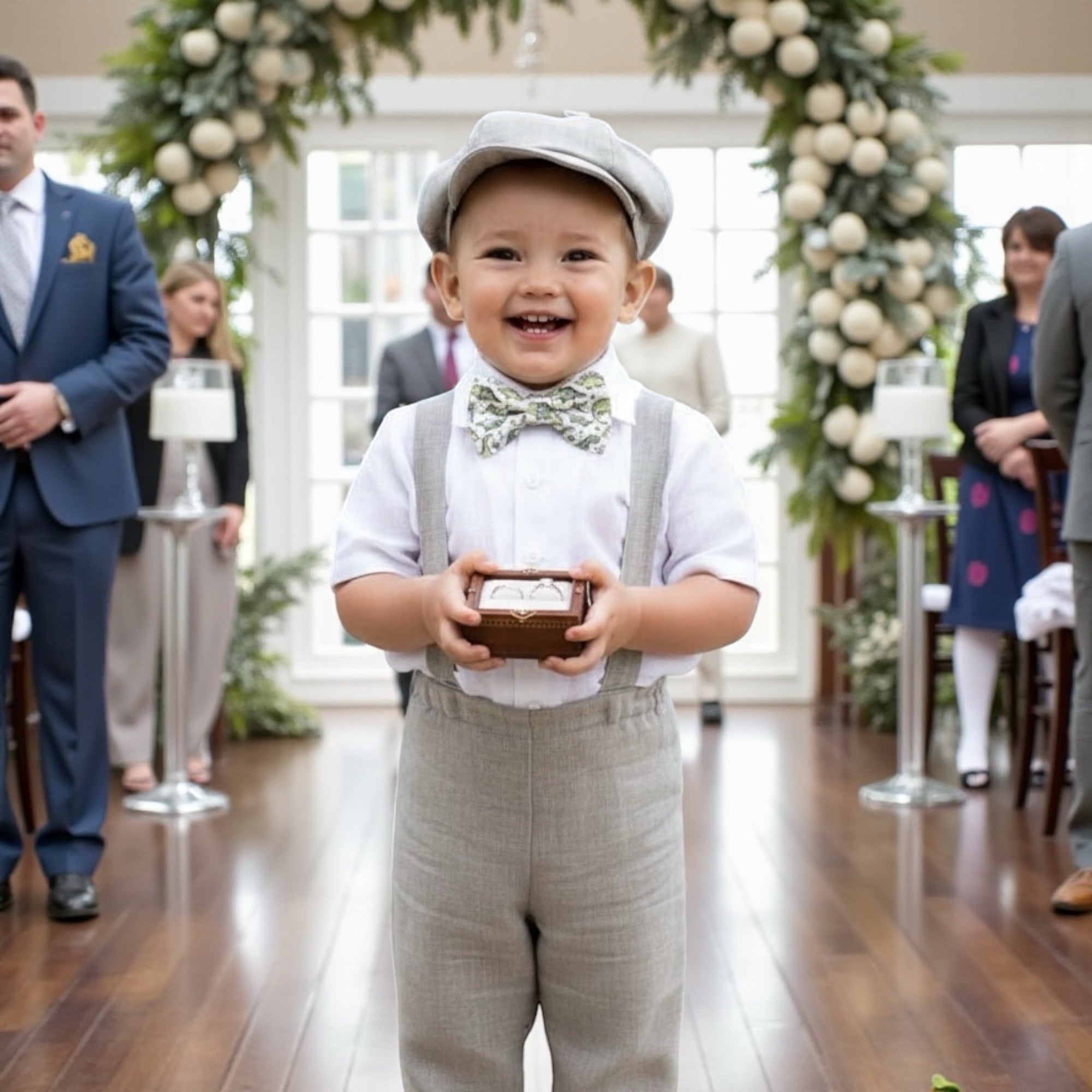 Ring bearer in a dinosaur bow tie holding a small box walking down the aisle at a wedding.