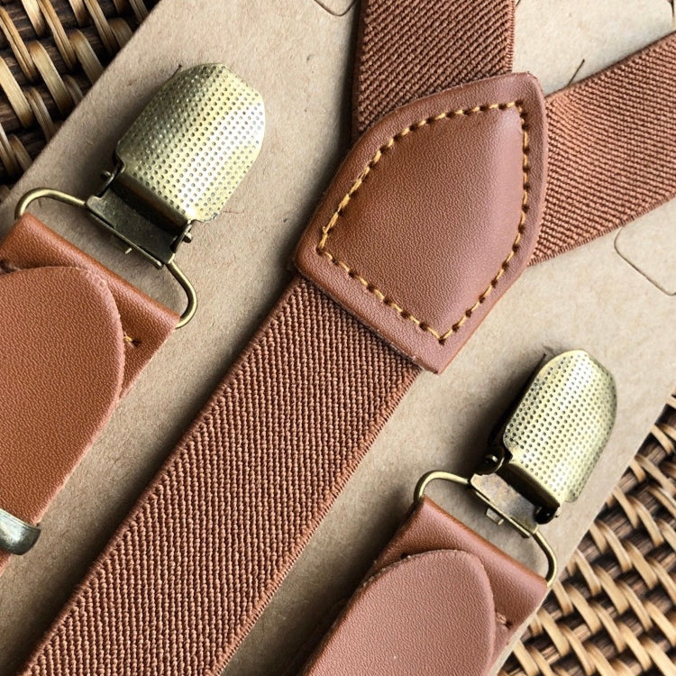 Wedding suspenders for groomsmen with bronze clips on a woven surface