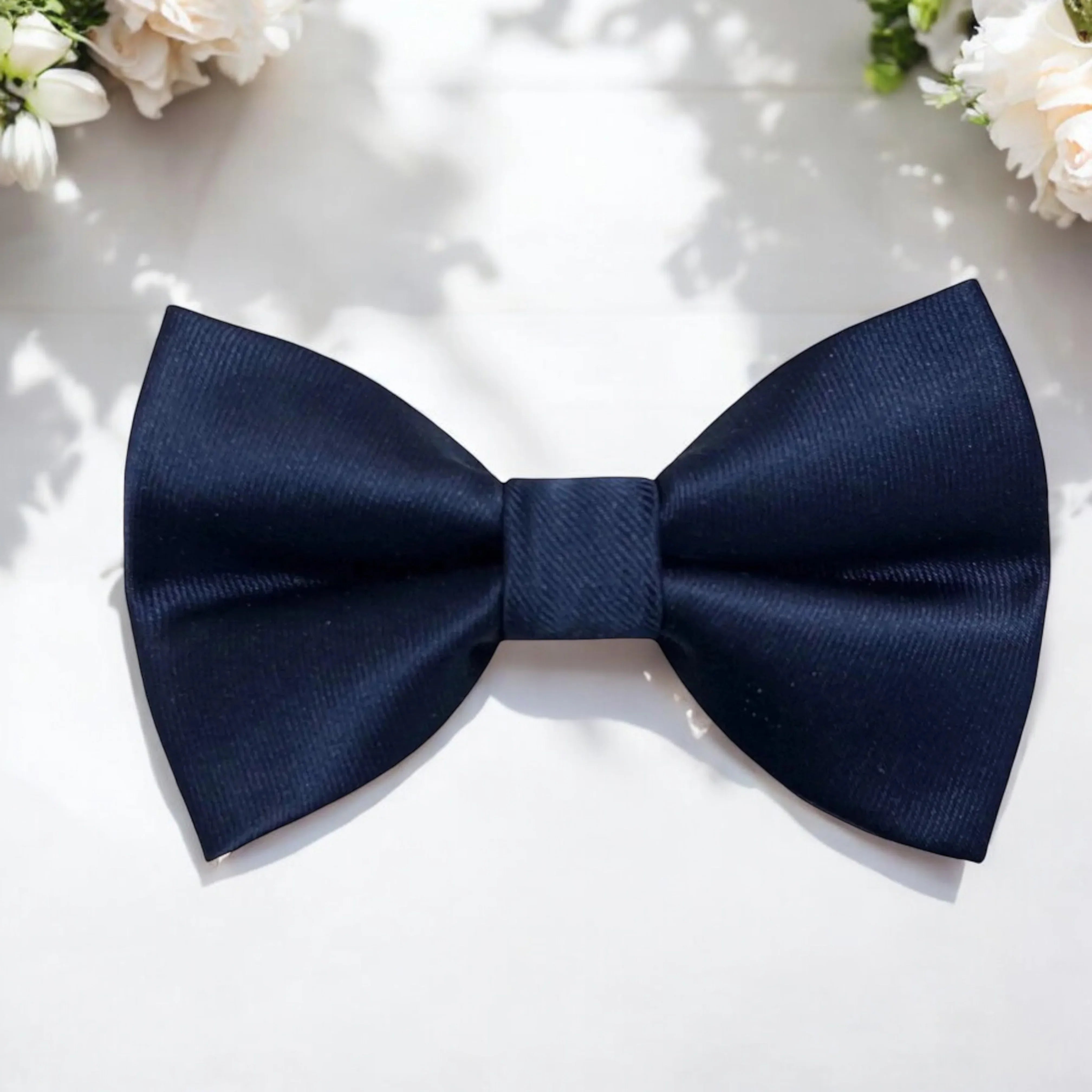 Size chart for pre-tied bow ties from The Bold Bow Tie detailing measurements across three sizes. Small is 3.5 inches wide and recommended for ages 6 months to 5 years. Medium is 4 inches wide and recommended for ages 6 to 12 years. Large is 4.5 inches wide and recommended for ages 13 years and up. Visual icons illustrate the relative sizes with horizontal arrows showing that width is measured from wingtip to wingtip. Bottom text notes that all bow ties are pre-tied and ready to add to your outfit.