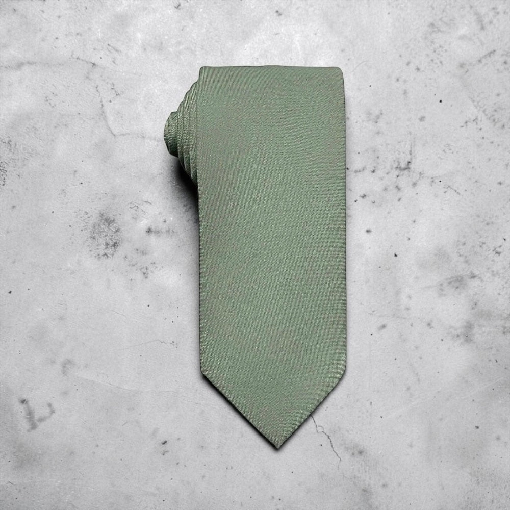 A sage green tie for men’s wedding necktie with a matching fabric neck loop, laid flat on a textured light gray concrete surface.