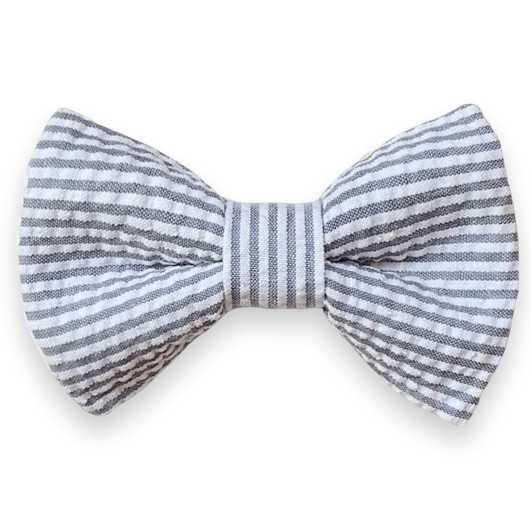 A gray seersucker bow tie with a striped pattern, pre-tied and displayed against a white background.