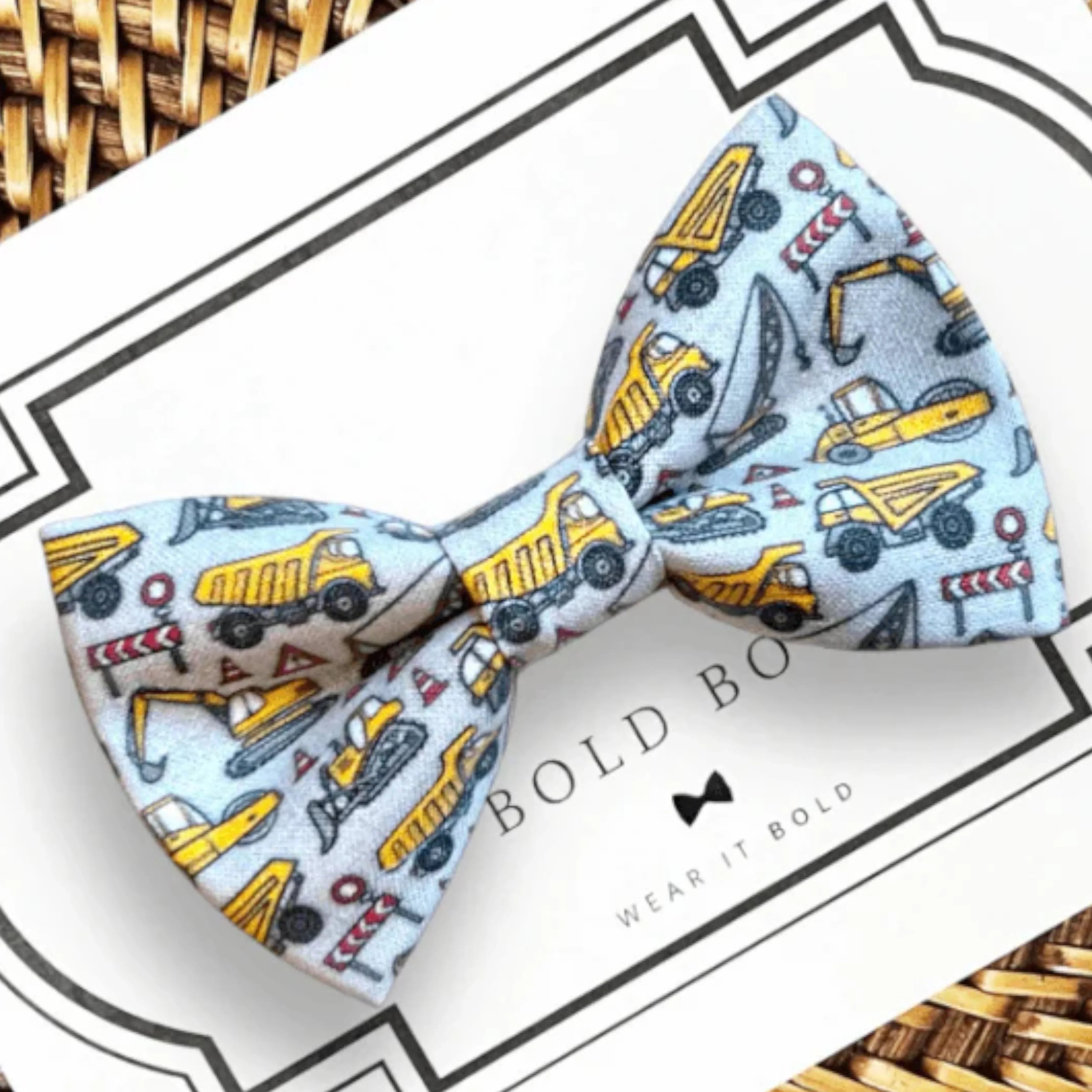 Light blue pet bow tie with construction vehicles on a white card backdrop