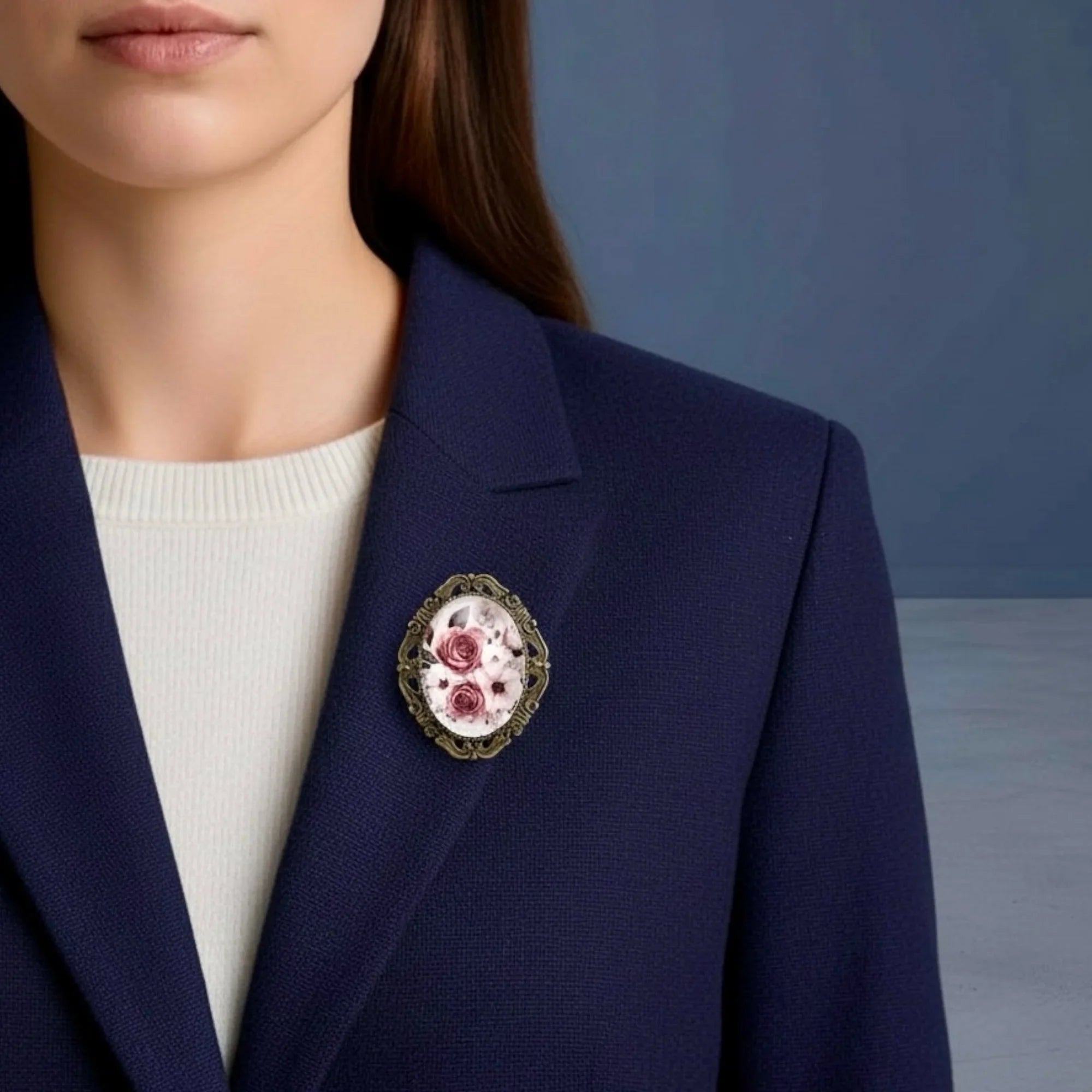 Navy blazer with a decorative floral brooch worn by a person against a blue background