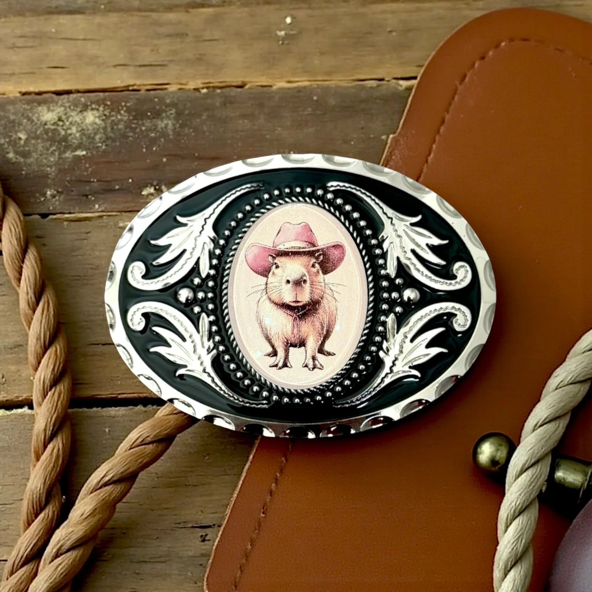 Belt buckle for men and women with a Capybara wearing a cowboy hat on a leather strap with rope