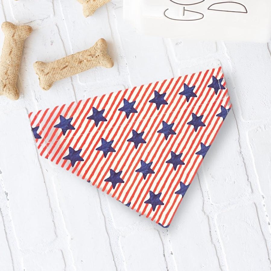 Red white and blue striped bandana with navy stars for a Fourth of July dog on a white surface