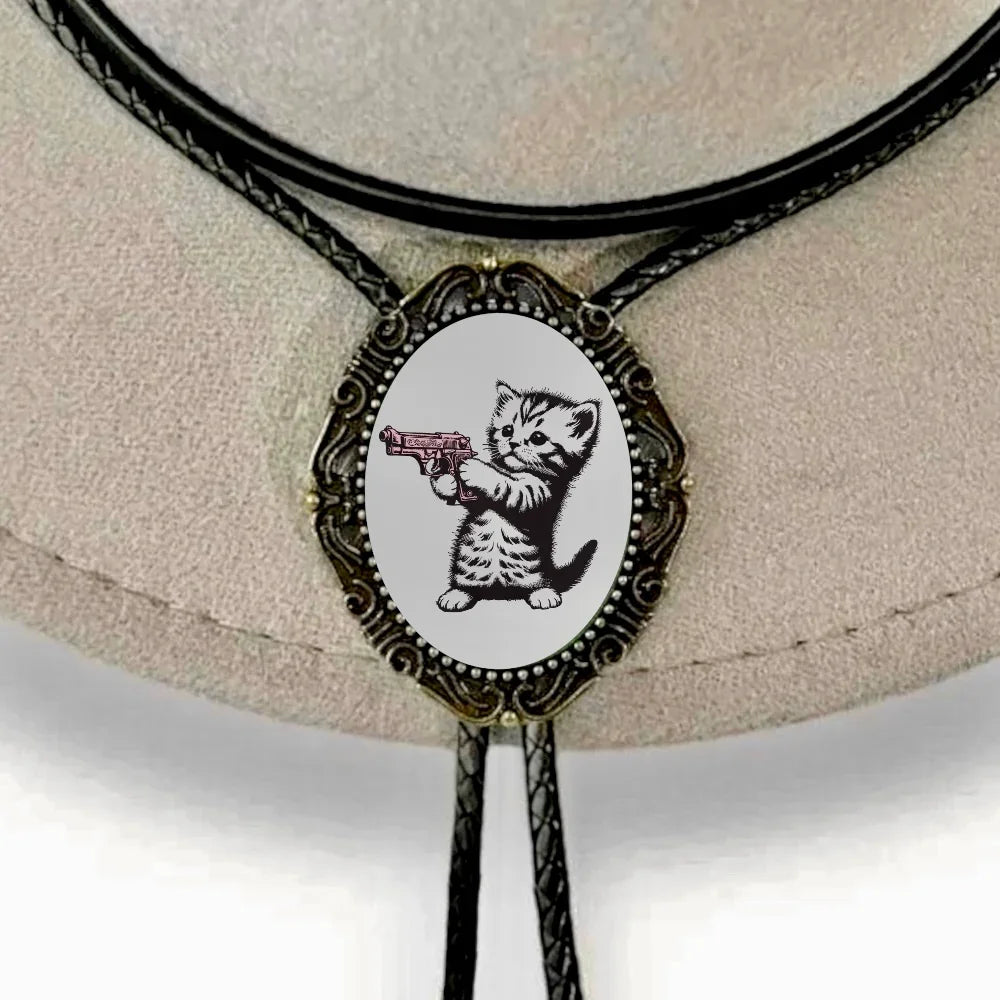 Bolo tie with black braided cord and an oval pendant featuring a cartoon kitten aiming a pistol