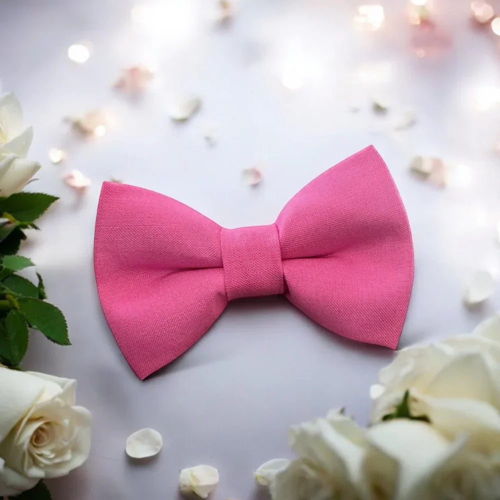 Pink bow tie for men boys and toddlers for a wedding surrounding by flowers.
