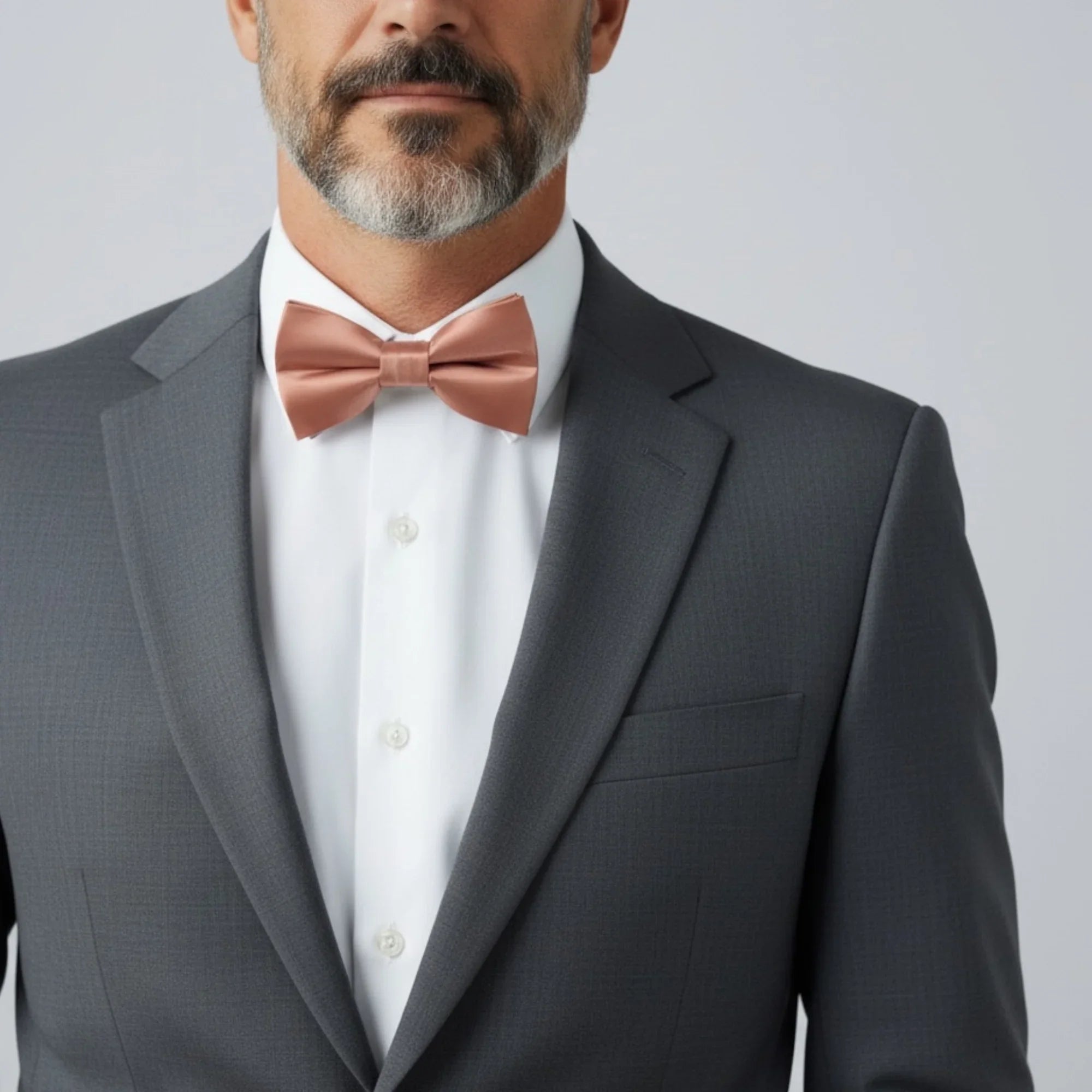 Desert coral bow tie worn by a man attending a wedding.