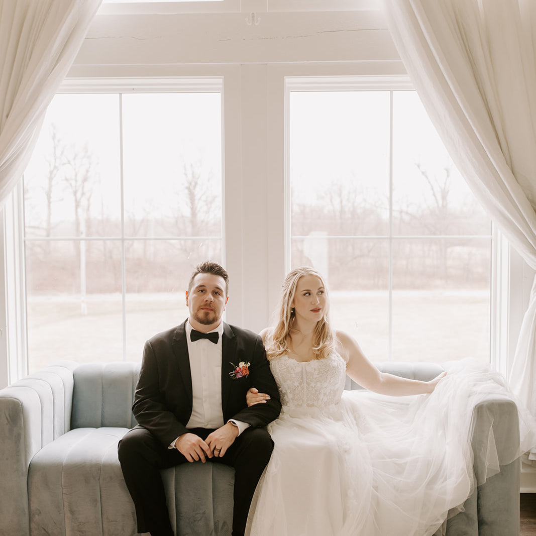 A groom wearing a satin black bow tie sitting next to his bride.