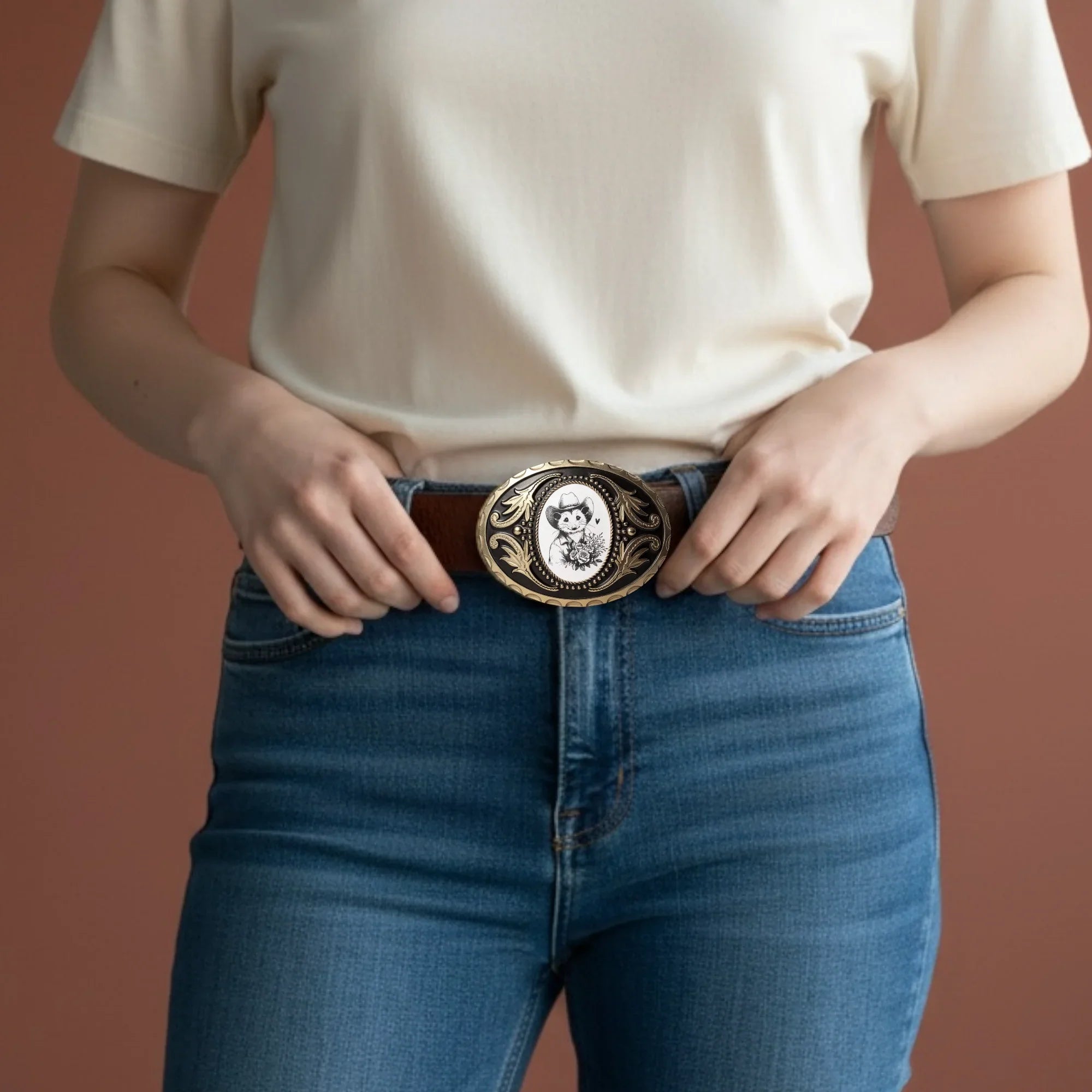 Person wearing blue jeans with a decorative opossum belt buckle for cowboys for Valentine’s Day.