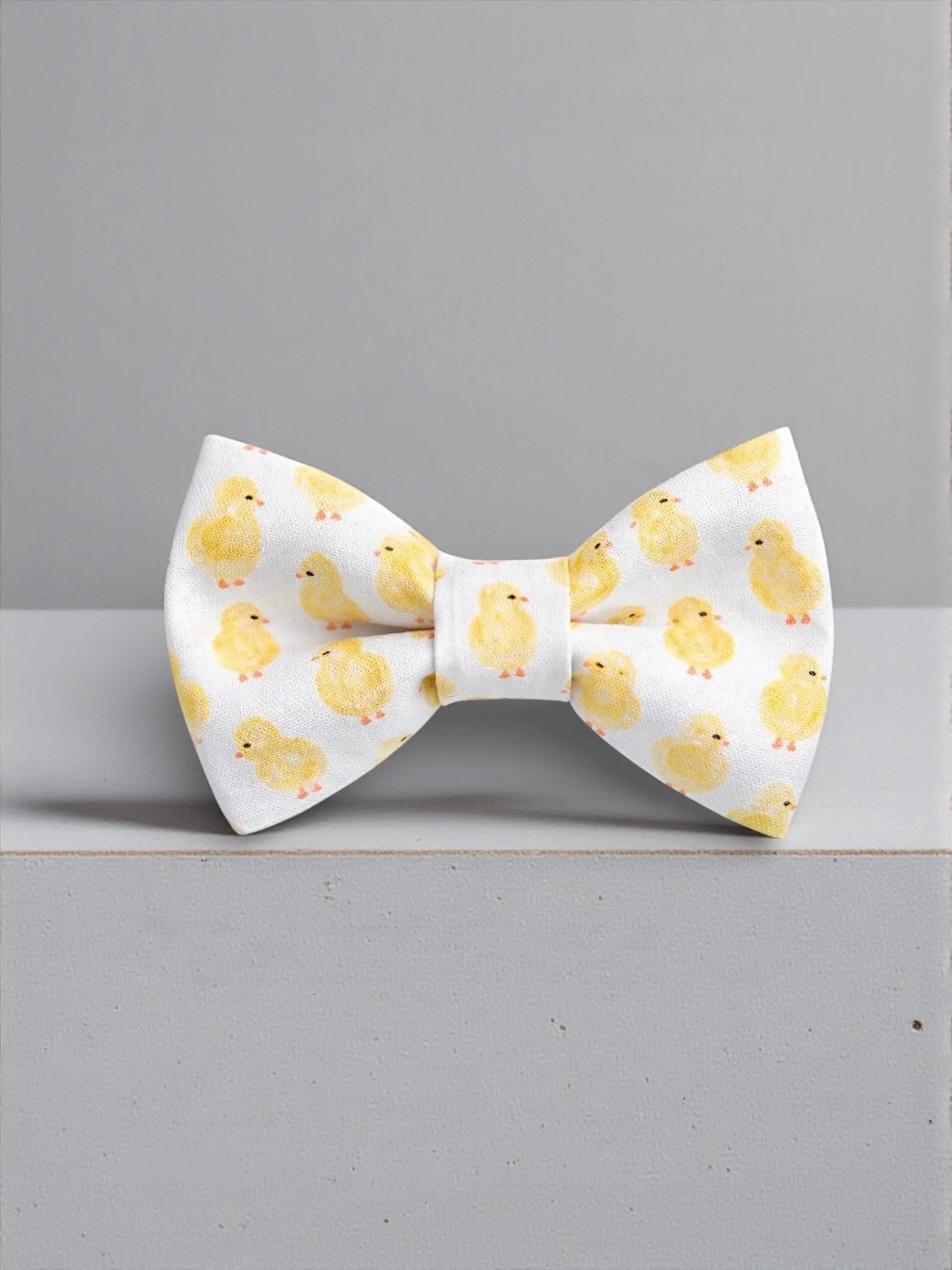 Size chart for pre-tied bow ties from The Bold Bow Tie detailing measurements across three sizes. Small is 3.5 inches wide and recommended for ages 6 months to 5 years. Medium is 4 inches wide and recommended for ages 6 to 12 years. Large is 4.5 inches wide and recommended for ages 13 years and up. Visual icons illustrate the relative sizes with horizontal arrows showing that width is measured from wingtip to wingtip. Bottom text notes that all bow ties are pre-tied and ready to add to your outfit.