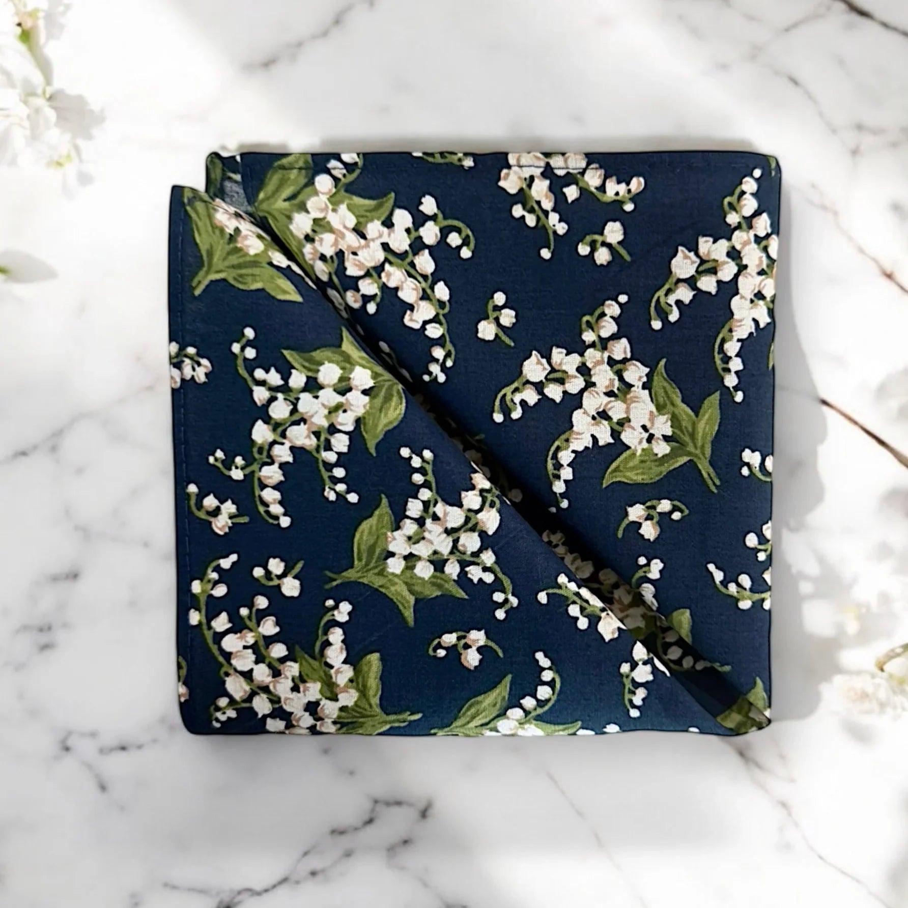 Navy blue pocket square with white floral pattern on a marble surface