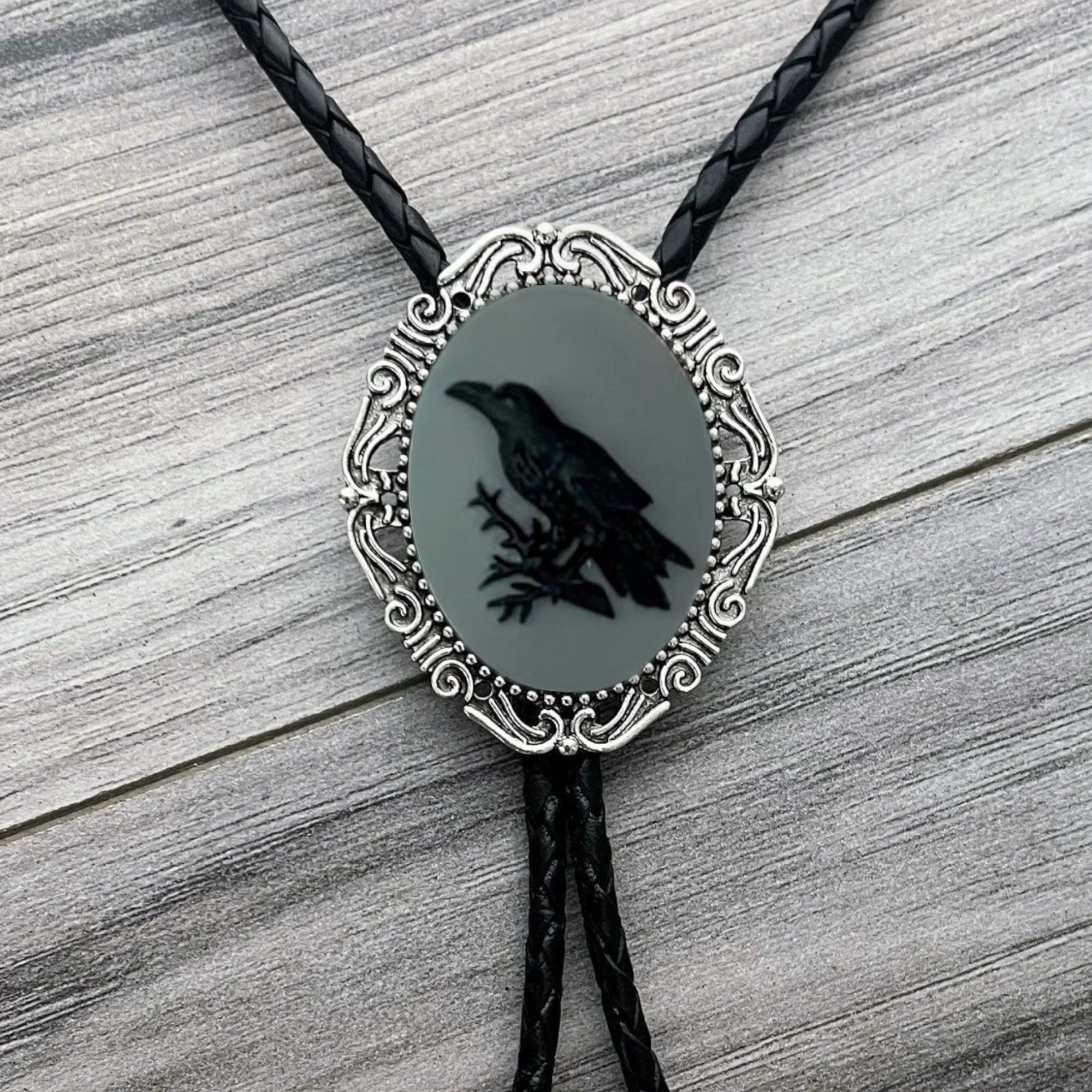 Silver back of a bolo tie with a clamp on a black leather cord