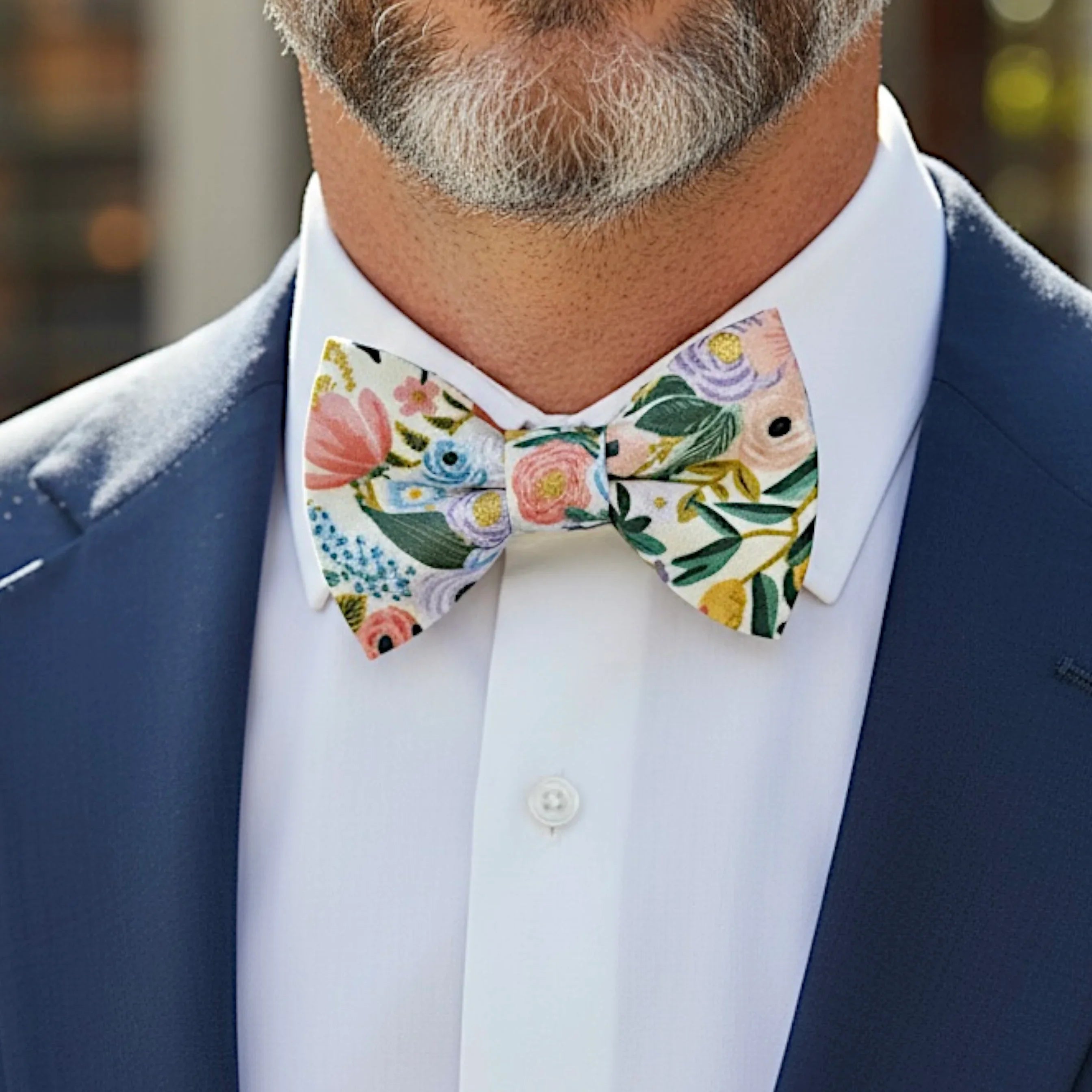 Size chart for pre-tied bow ties from The Bold Bow Tie detailing measurements across three sizes. Small is 3.5 inches wide and recommended for ages 6 months to 5 years. Medium is 4 inches wide and recommended for ages 6 to 12 years. Large is 4.5 inches wide and recommended for ages 13 years and up. Visual icons illustrate the relative sizes with horizontal arrows showing that width is measured from wingtip to wingtip. Bottom text notes that all bow ties are pre-tied and ready to add to your outfit.