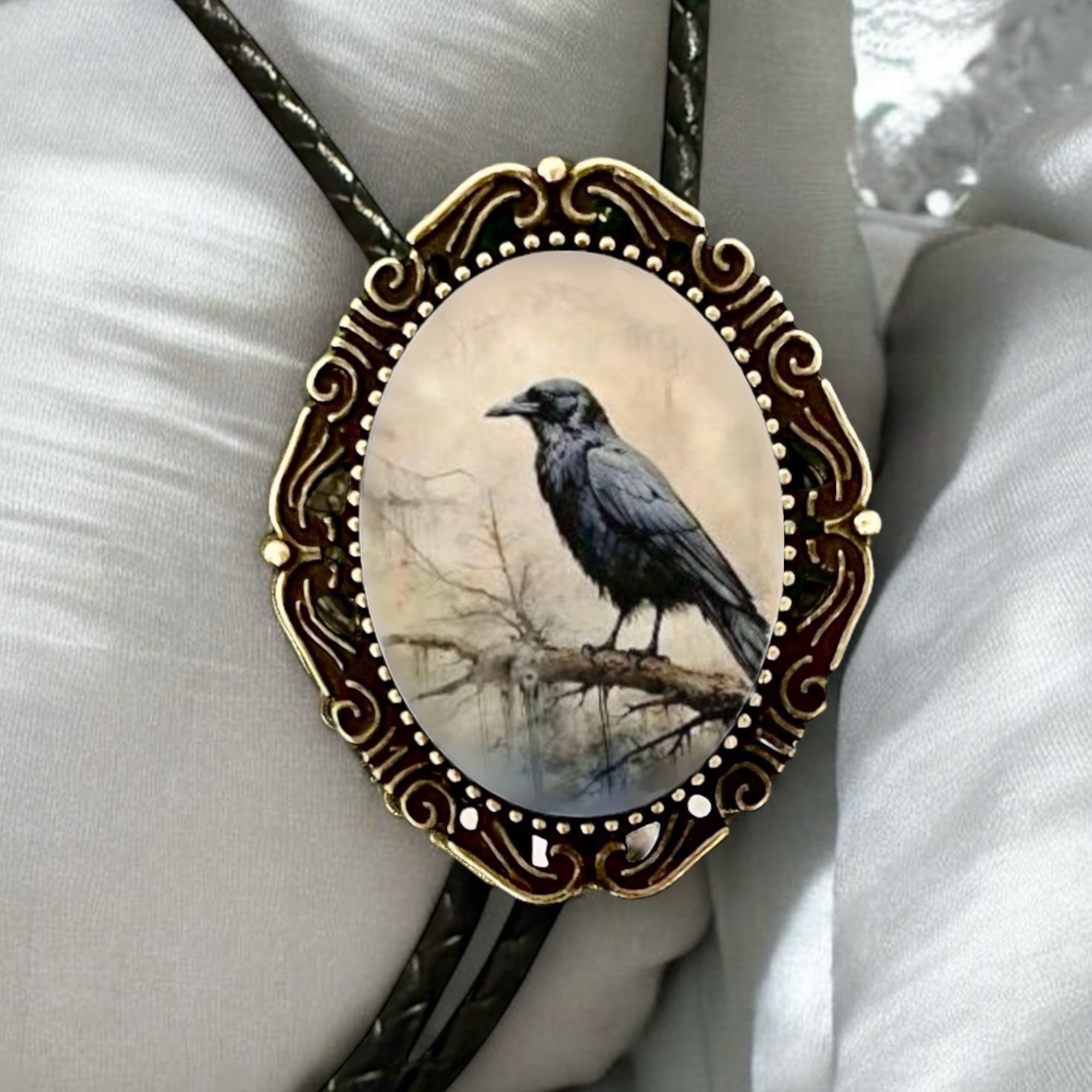 Raven bolo tie and black leather cord on white pillow