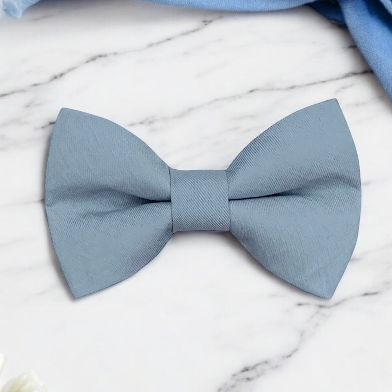 Dusty blue bow tie on a marble surface