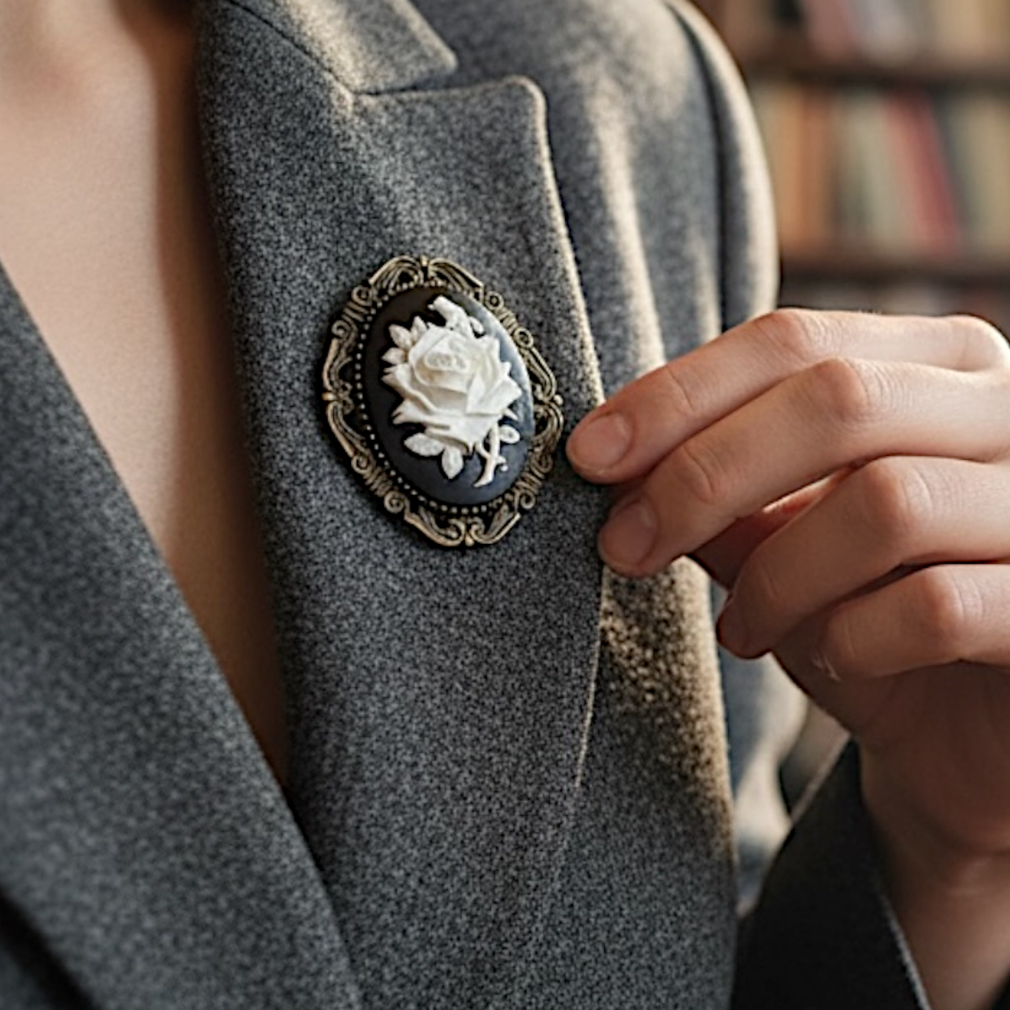 Person wearing a gray blazer with a decorative vintage brooch featuring a white rose design.