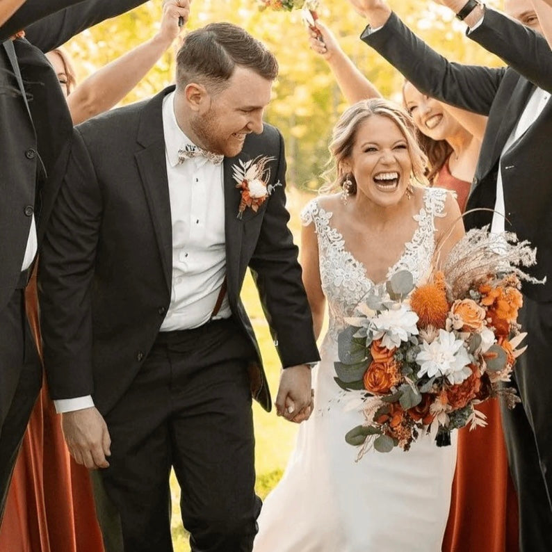Wedding couple walking through a celebratory crowd with autumn-themed bouquets.