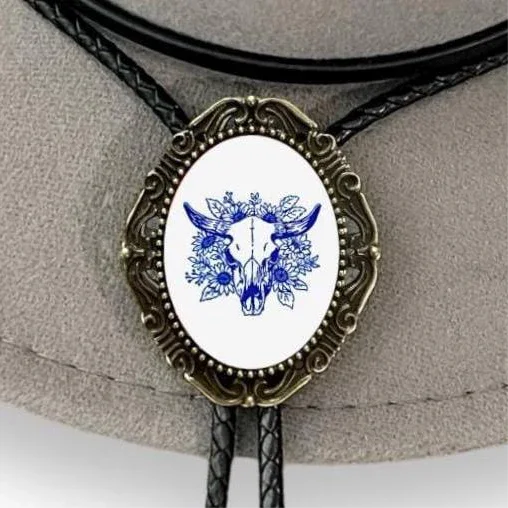 Bolo tie with blue deer skull design on a white background, on a beige surface.