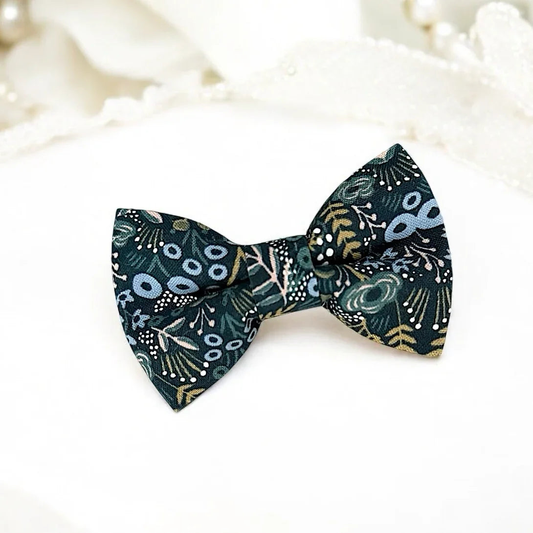 Size chart for pre-tied bow ties from The Bold Bow Tie detailing measurements across three sizes. Small is 3.5 inches wide and recommended for ages 6 months to 5 years. Medium is 4 inches wide and recommended for ages 6 to 12 years. Large is 4.5 inches wide and recommended for ages 13 years and up. Visual icons illustrate the relative sizes with horizontal arrows showing that width is measured from wingtip to wingtip. Bottom text notes that all bow ties are pre-tied and ready to add to your outfit.