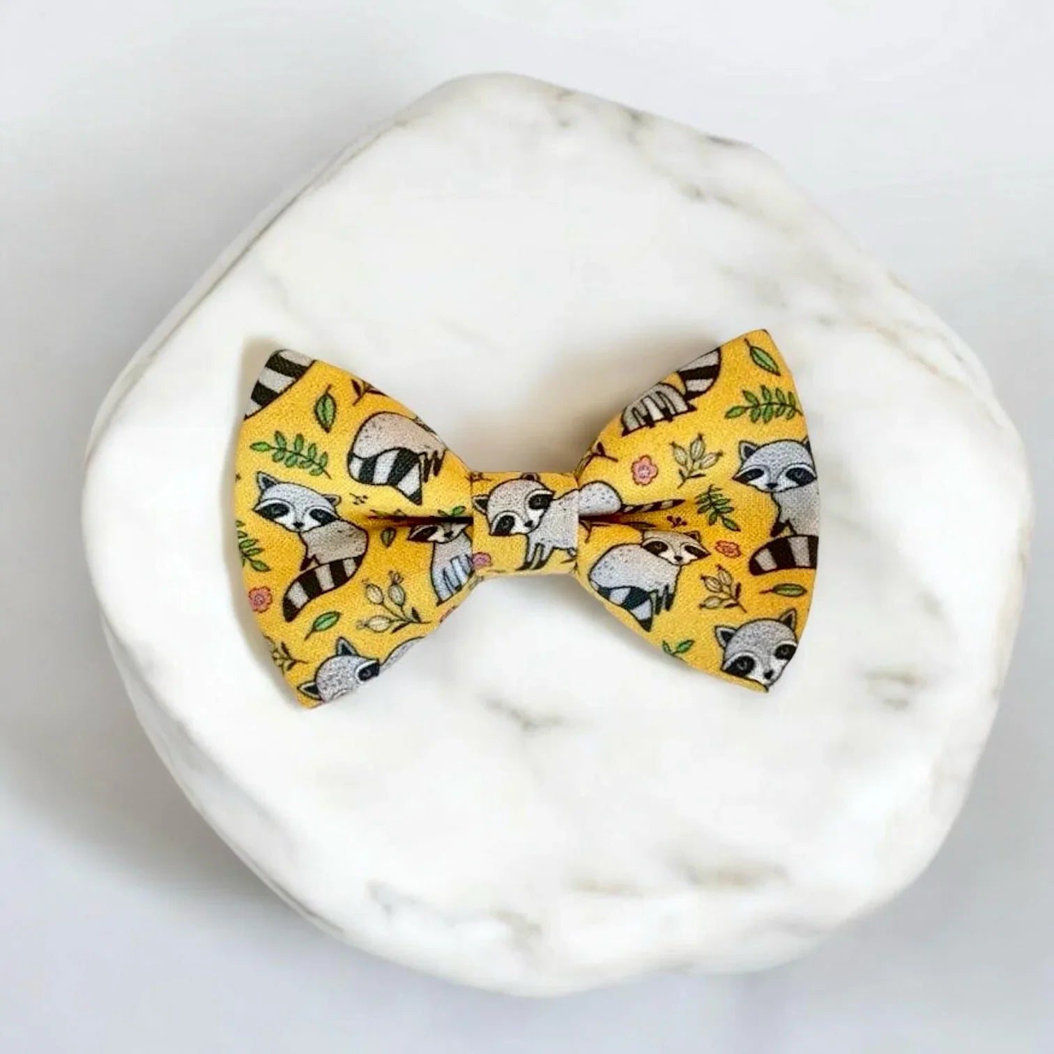 Yellow raccoon patterned bow tie for dogs or cats on a white background