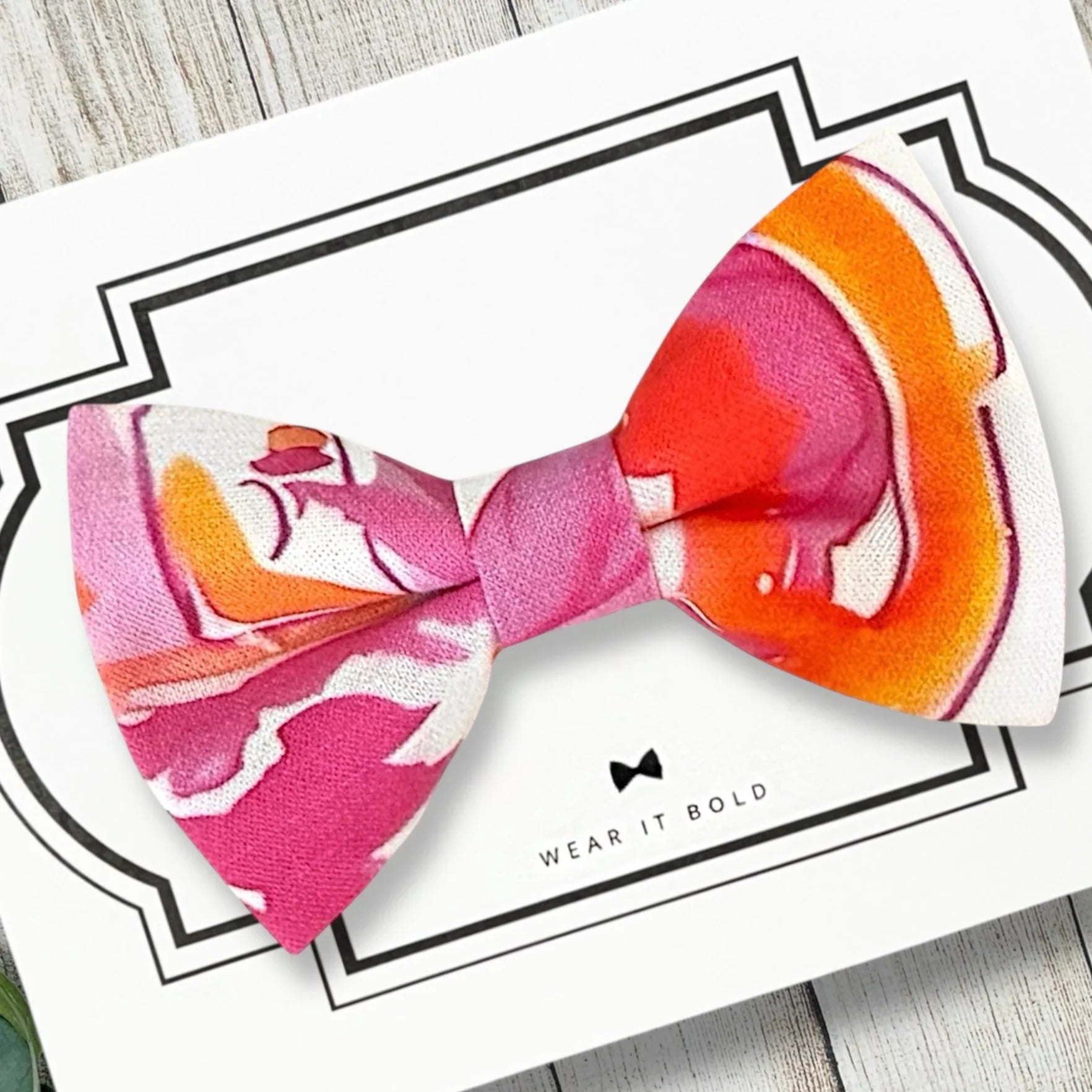 Orange and pink watercolor bow tie for dogs or cats displayed on a white card.