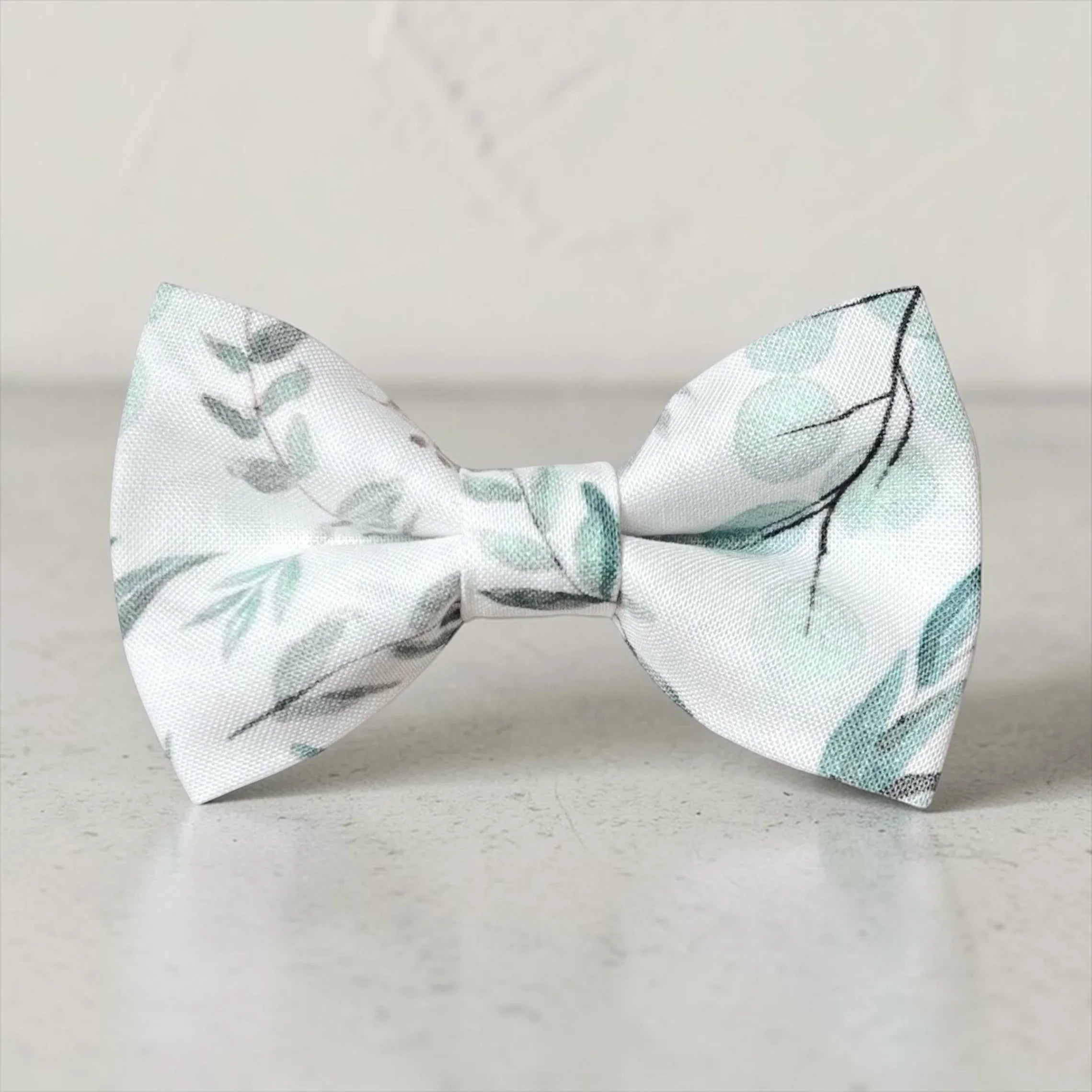 Promotional graphic from The Bold Bow Tie titled Let's Connect. On the left, a model with wavy blonde hair wears a white hair bow with a blue floral pattern. Circular text reads Handmade, 5-Star Rated, Premiere Customer Service. On the right, an Instagram icon prompts to follow @theboldbowtie and message for a coupon code. Below, an email icon encourages signing up for the VIP email list for the latest news and exclusive discounts, noting that the link to join is in the description.