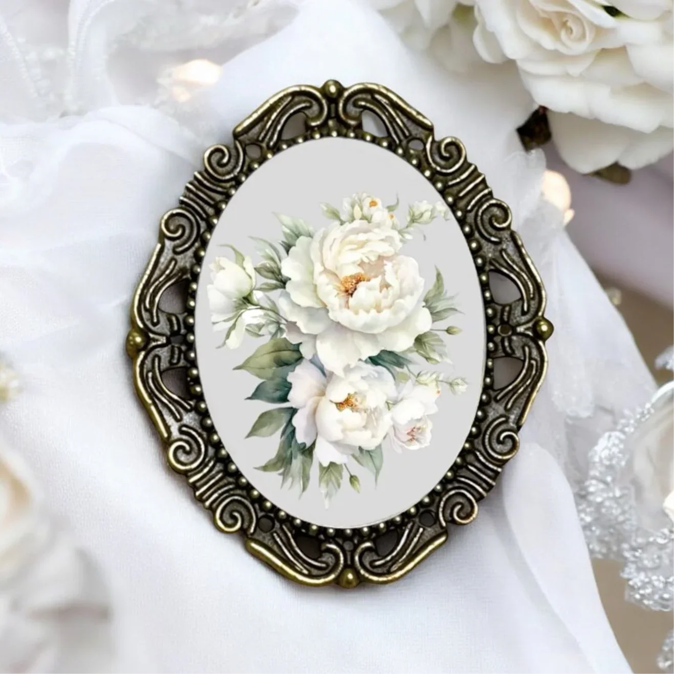 Decorative brooch with floral design and ornate gold frame on a white fabric background